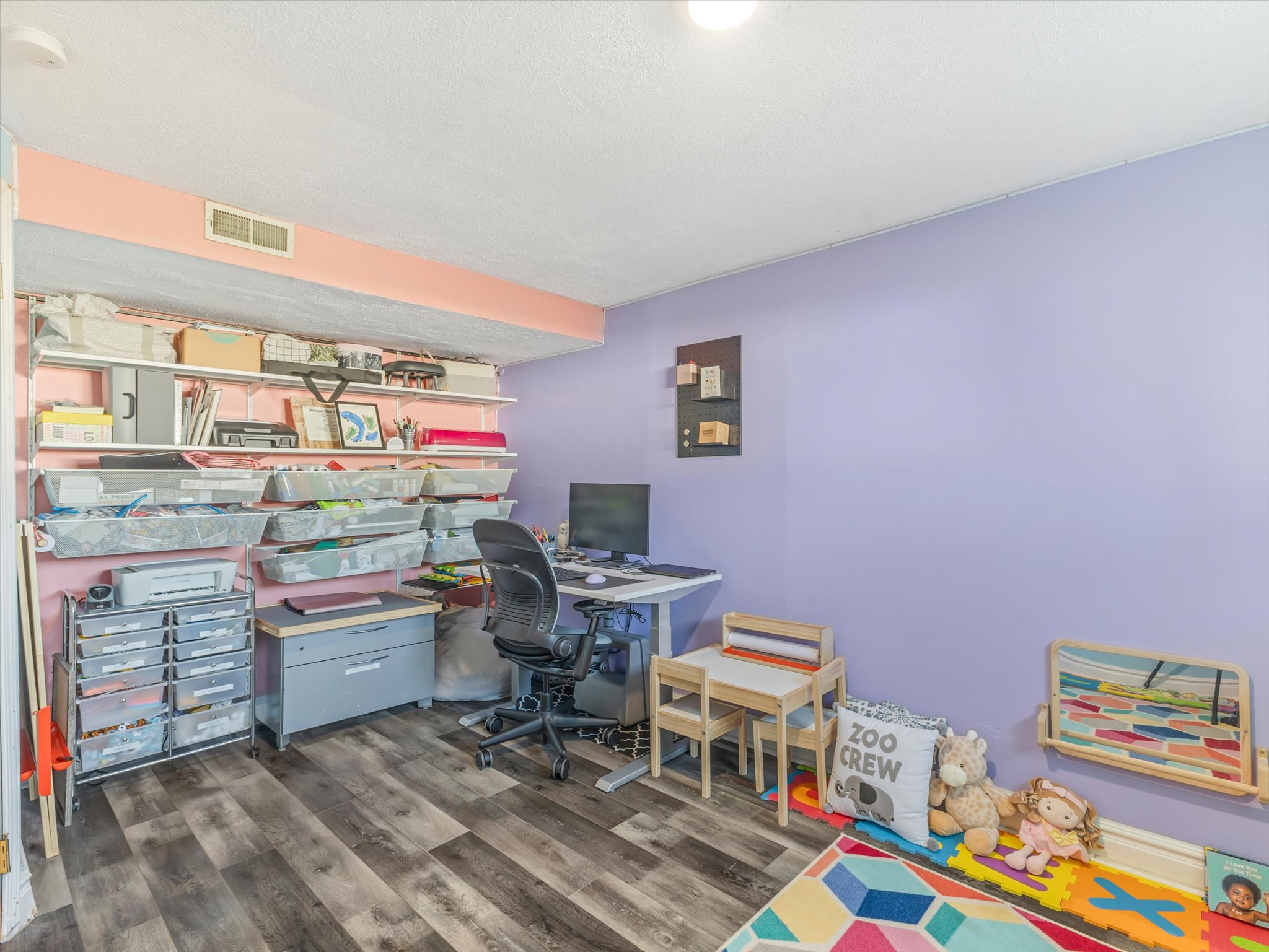 Interior room featuring wood-finish flooring, recessed lighting, and a wall-mounted shelving system