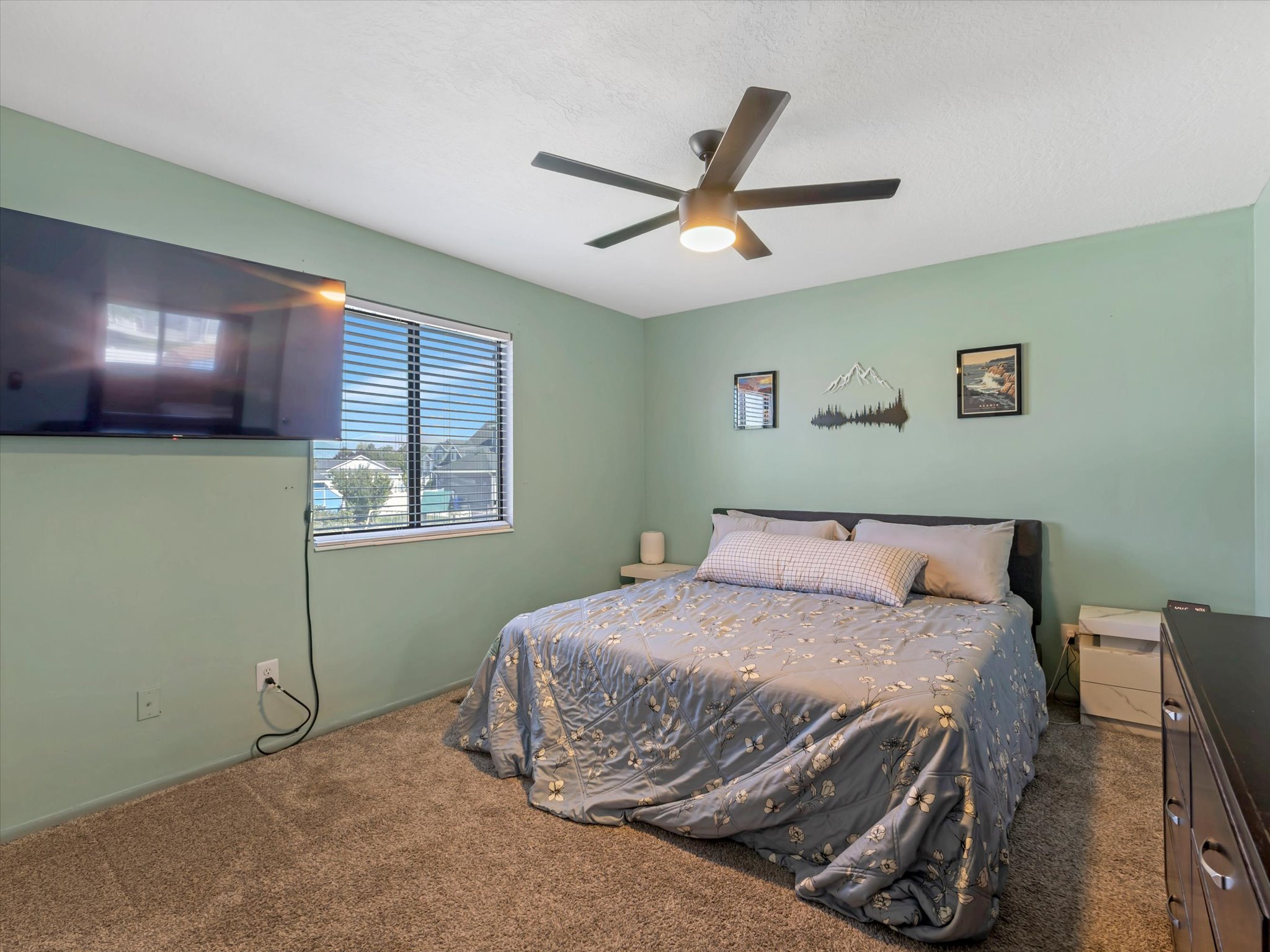 Carpeted room featuring a ceiling fan with integrated lighting, a window with horizontal blinds, and light green wall paint