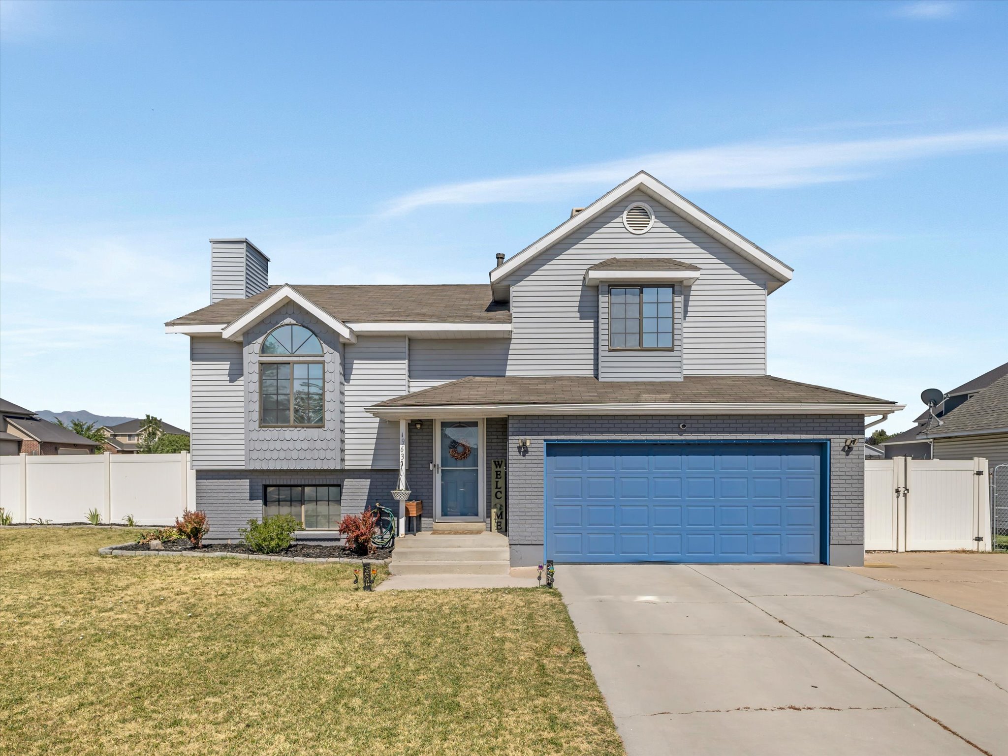 Two-story residence featuring light gray siding with a contrasting blue garage door