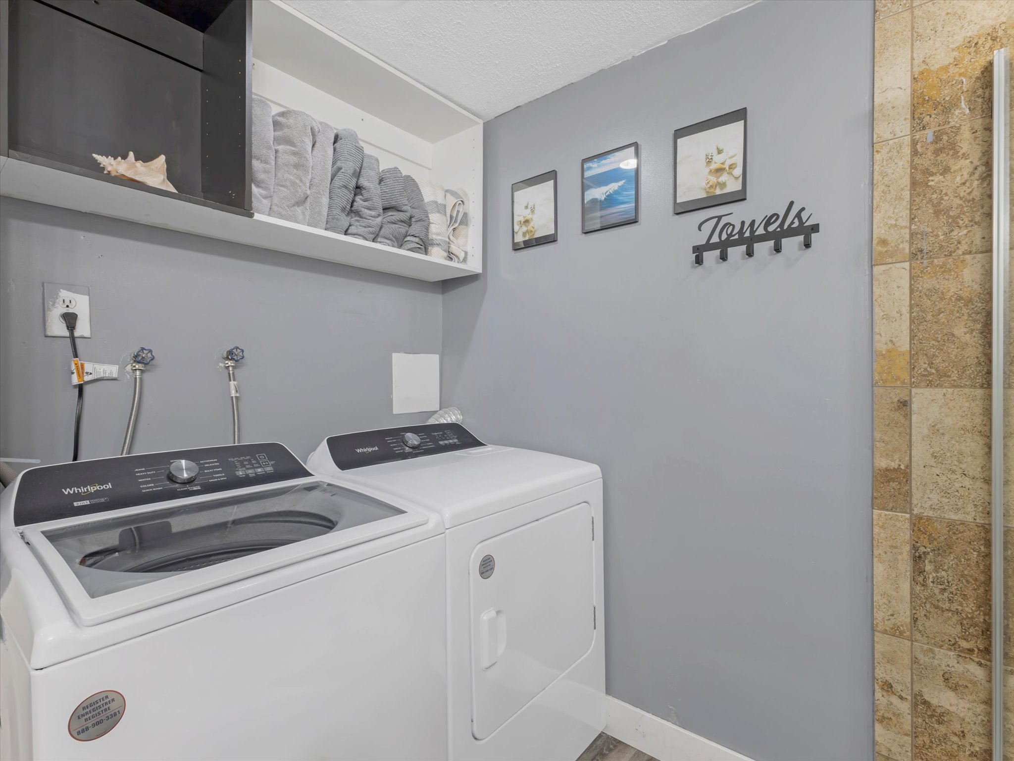 Dedicated laundry area featuring modern appliances, wall-mounted shelving, and a neutral color palette