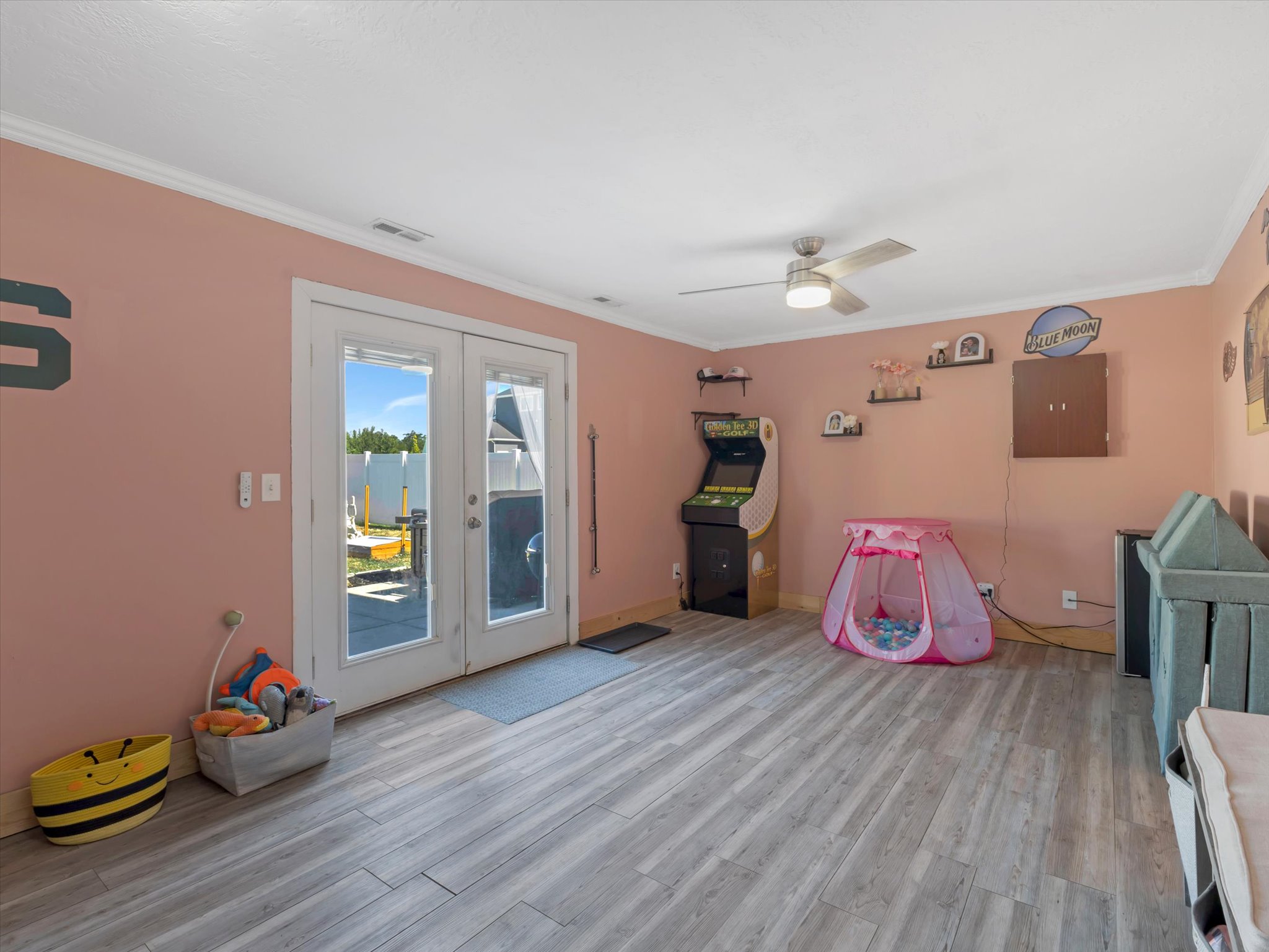 Spacious room featuring light wood-finish flooring, crown molding, and a ceiling fan