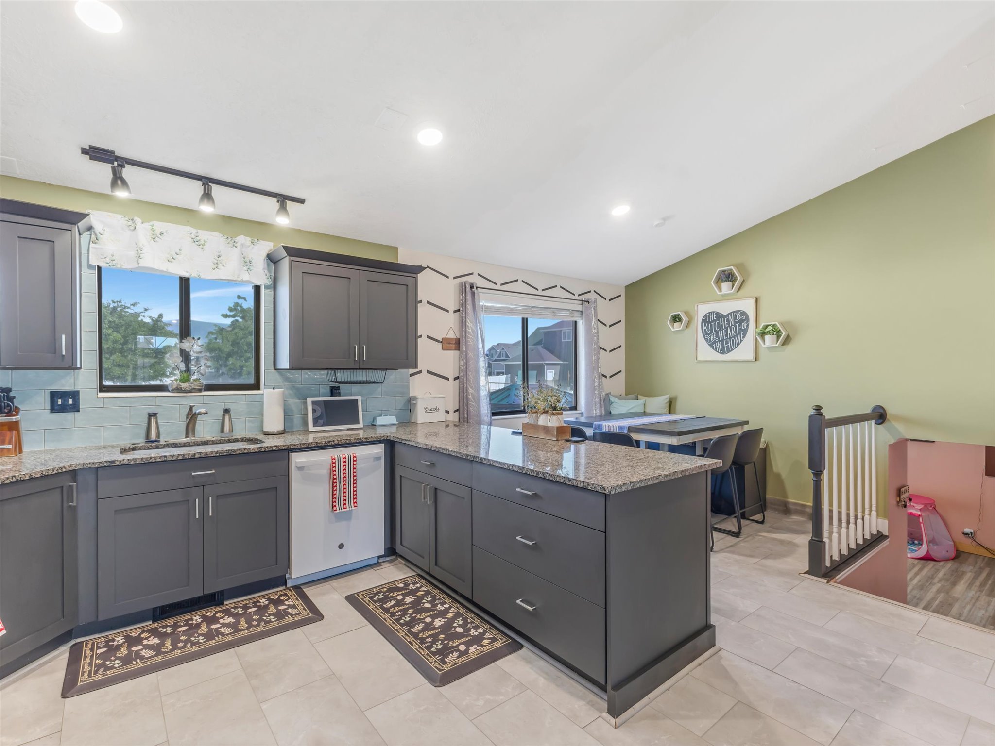 Modern kitchen featuring dark grey cabinetry with chrome hardware, speckled countertops, and a subway tile backsplash