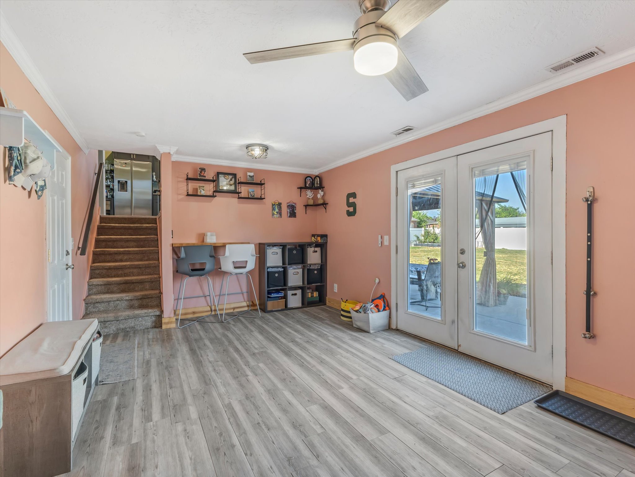 Living space featuring wood-finish flooring, a ceiling fan with integrated lighting, and a double-door exterior access