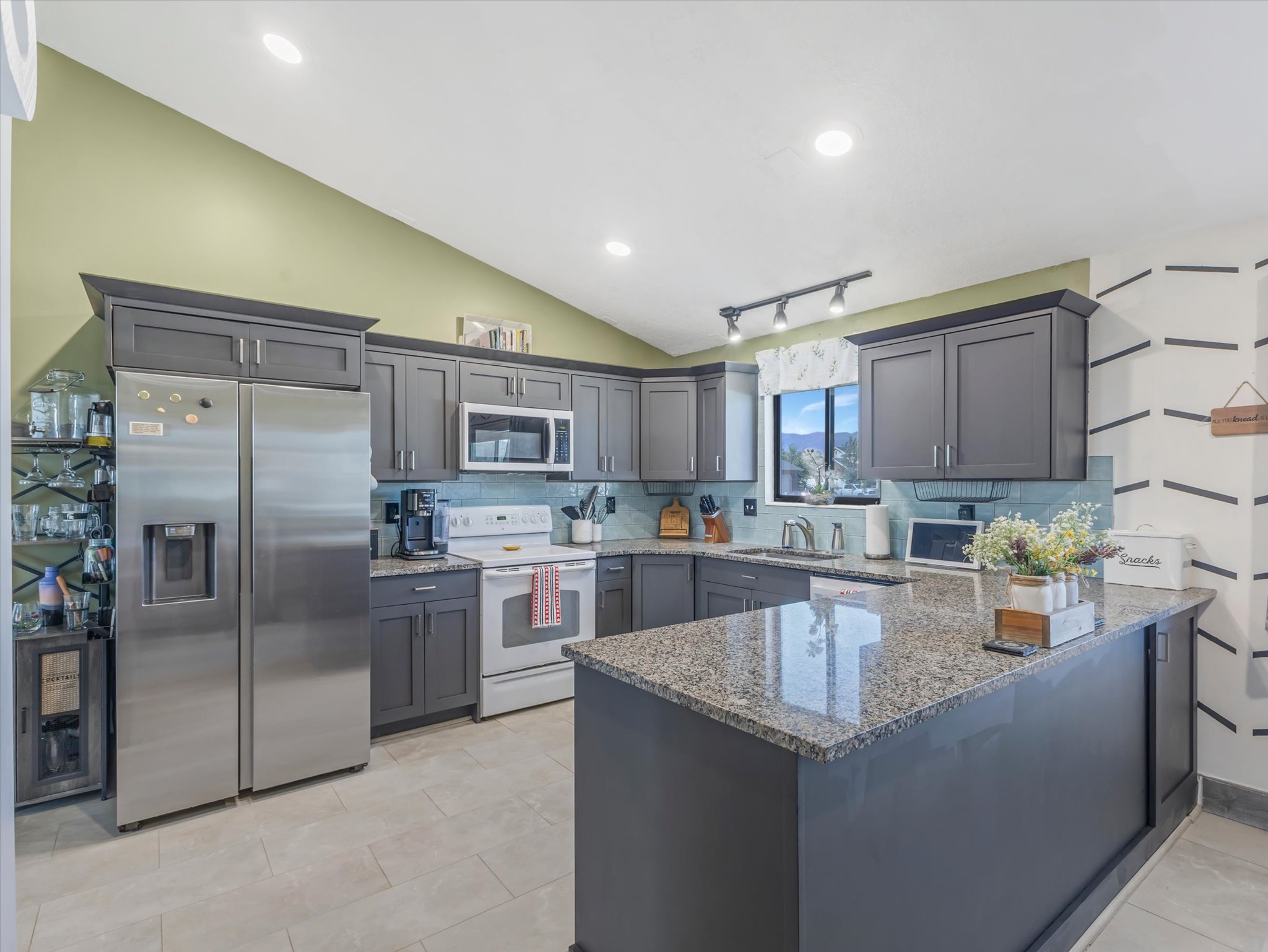 Kitchen featuring dark gray cabinetry, light granite countertops, and a subway tile backsplash
