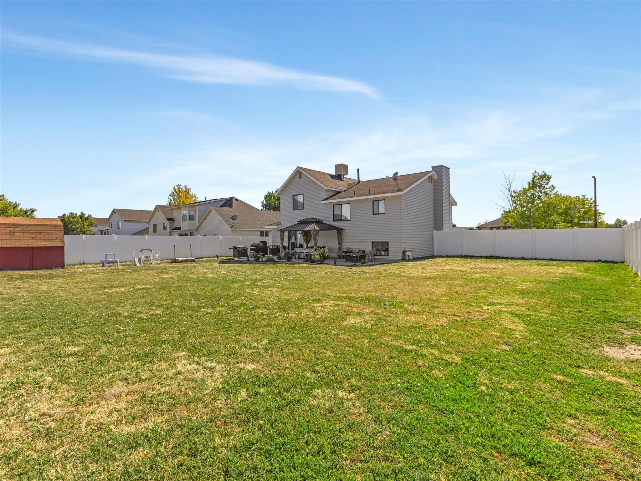 Expansive rear yard with a perimeter vinyl fence and a detached storage shed