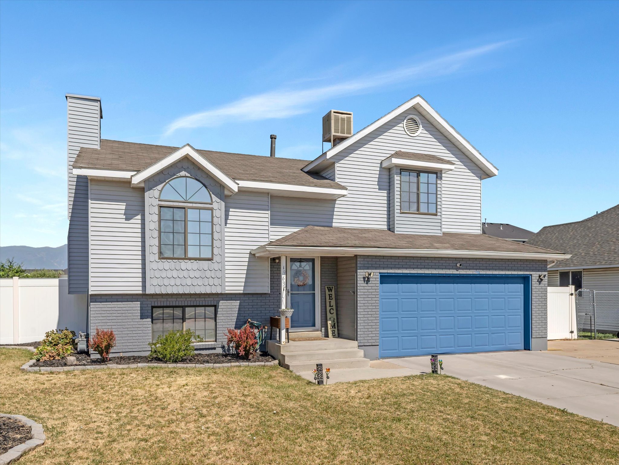 Two-story residence featuring light gray siding and a gray brick foundation