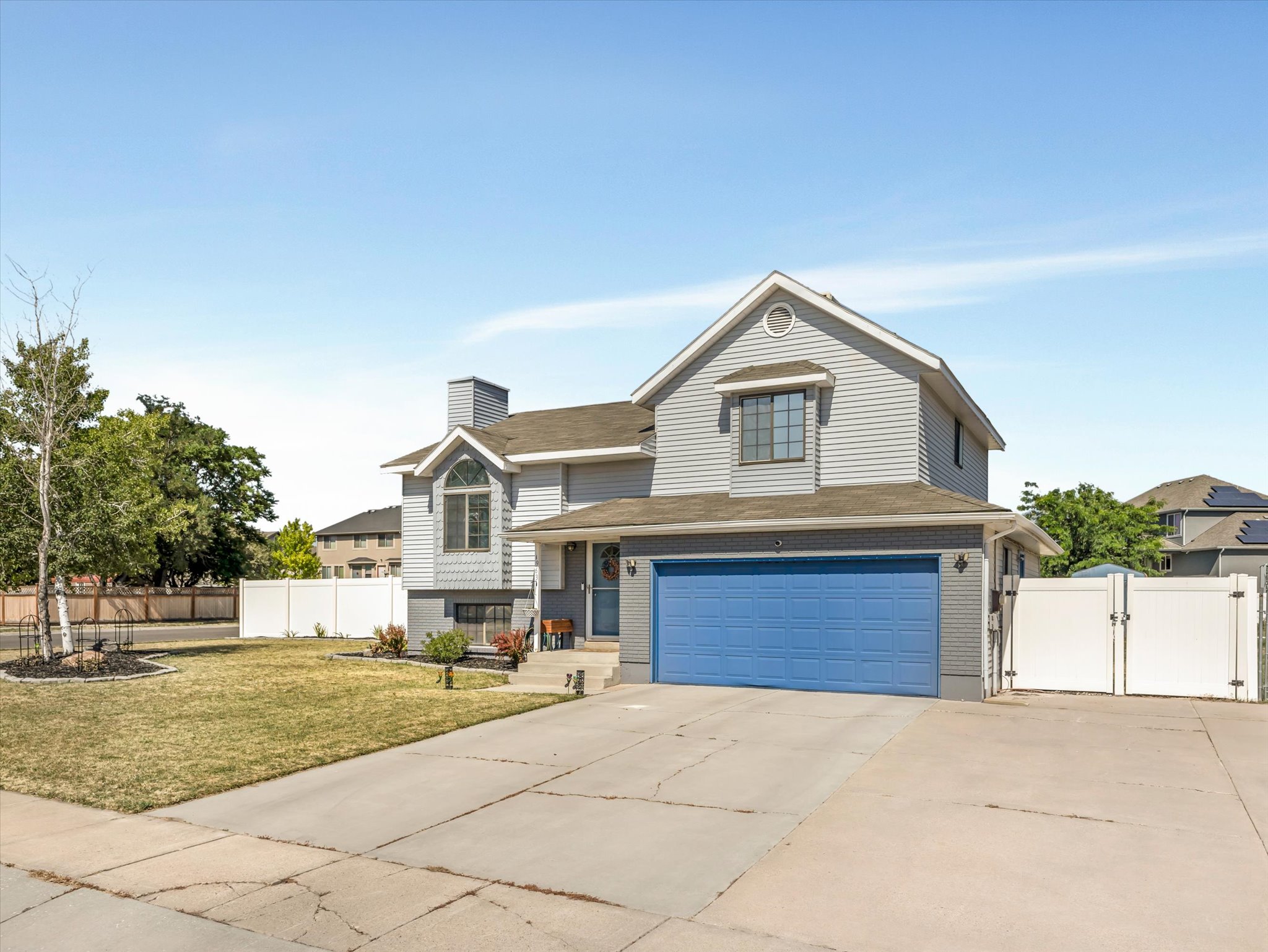 Two-story residence featuring light gray siding and a bright blue garage door