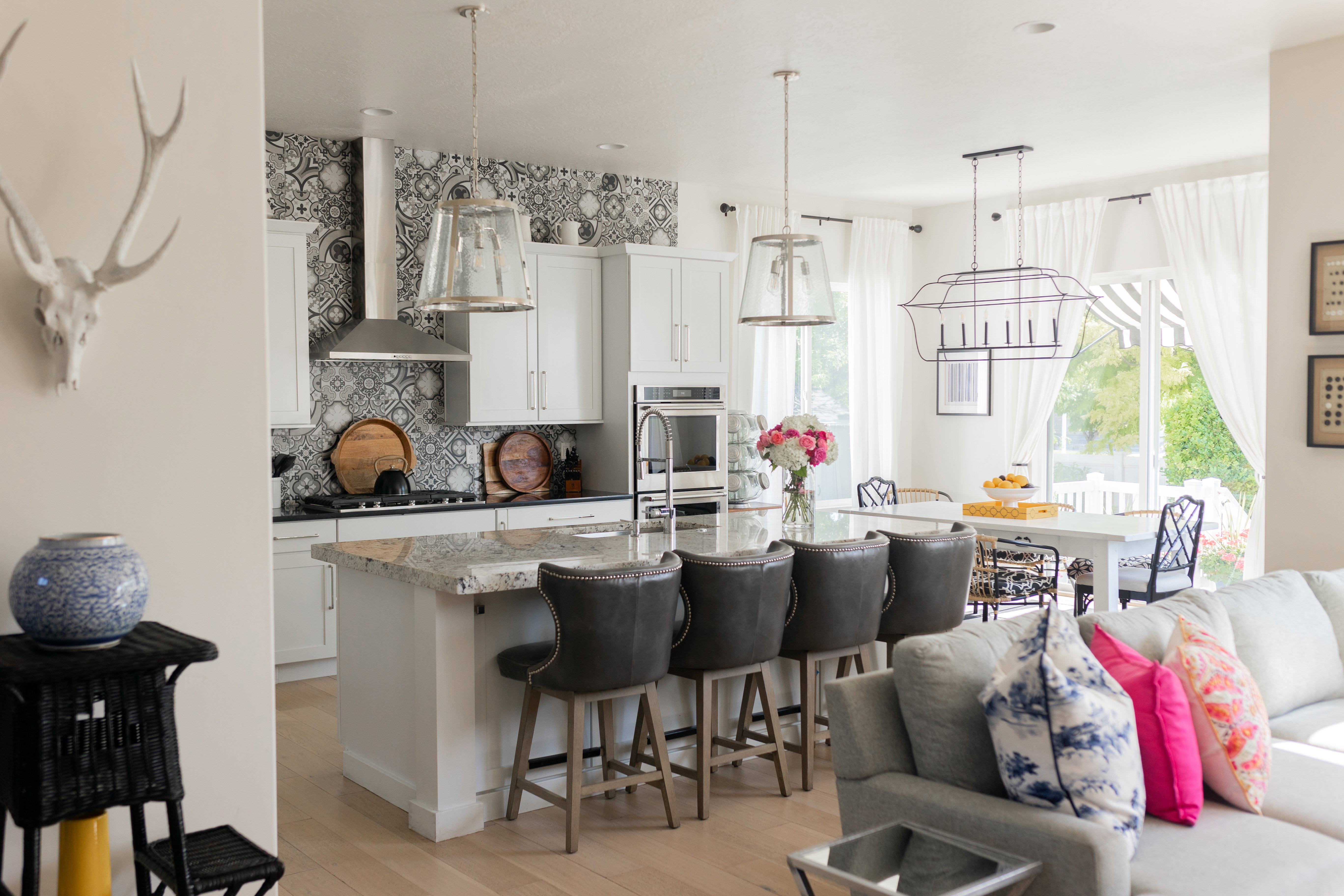 Open-concept kitchen and dining area featuring a kitchen island with seating, pendant lighting, built-in appliances, and light wood-finish flooring