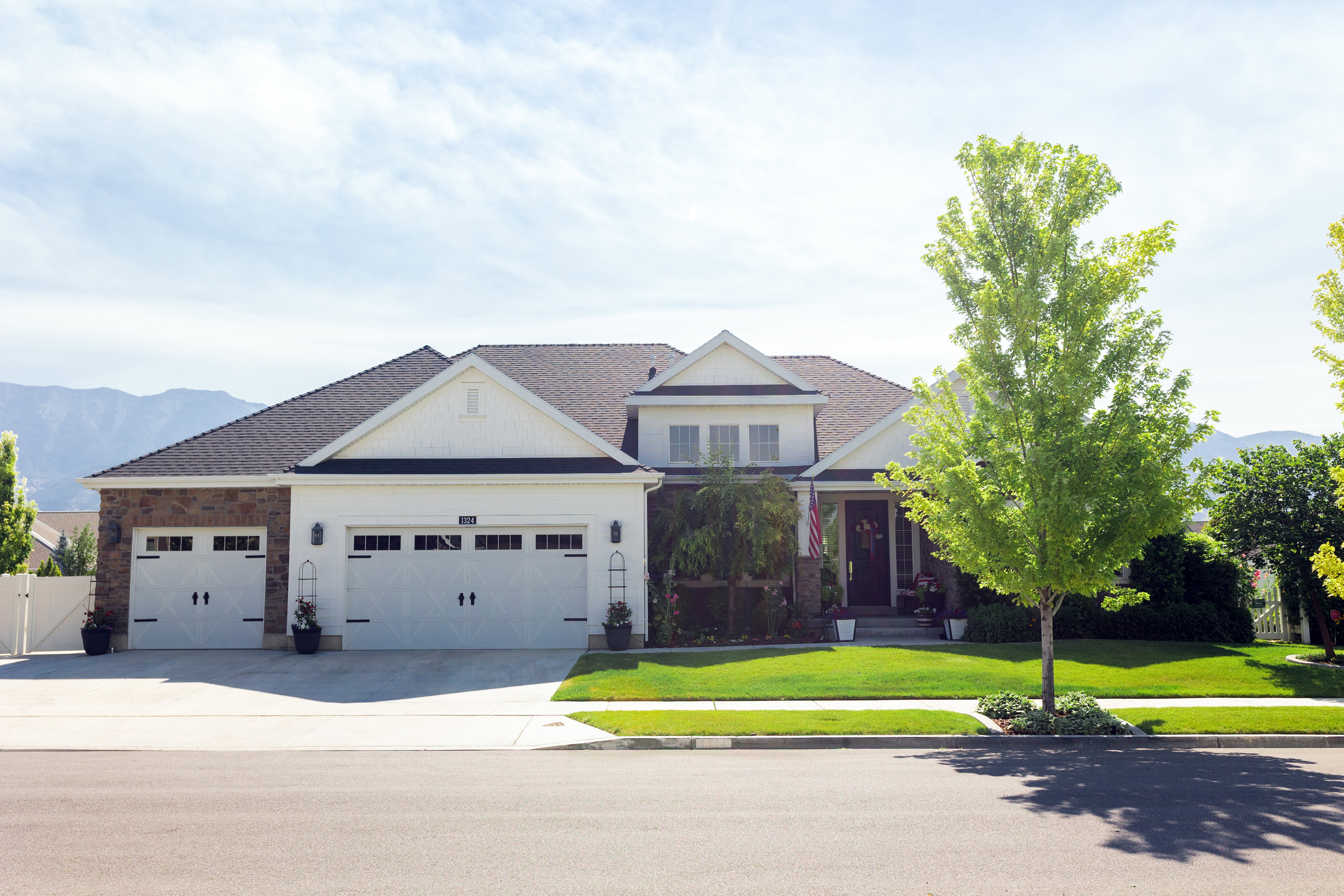 Traditional-style residence featuring a combination of over grouted stone and siding, a three-car garage, and additional concrete parking.