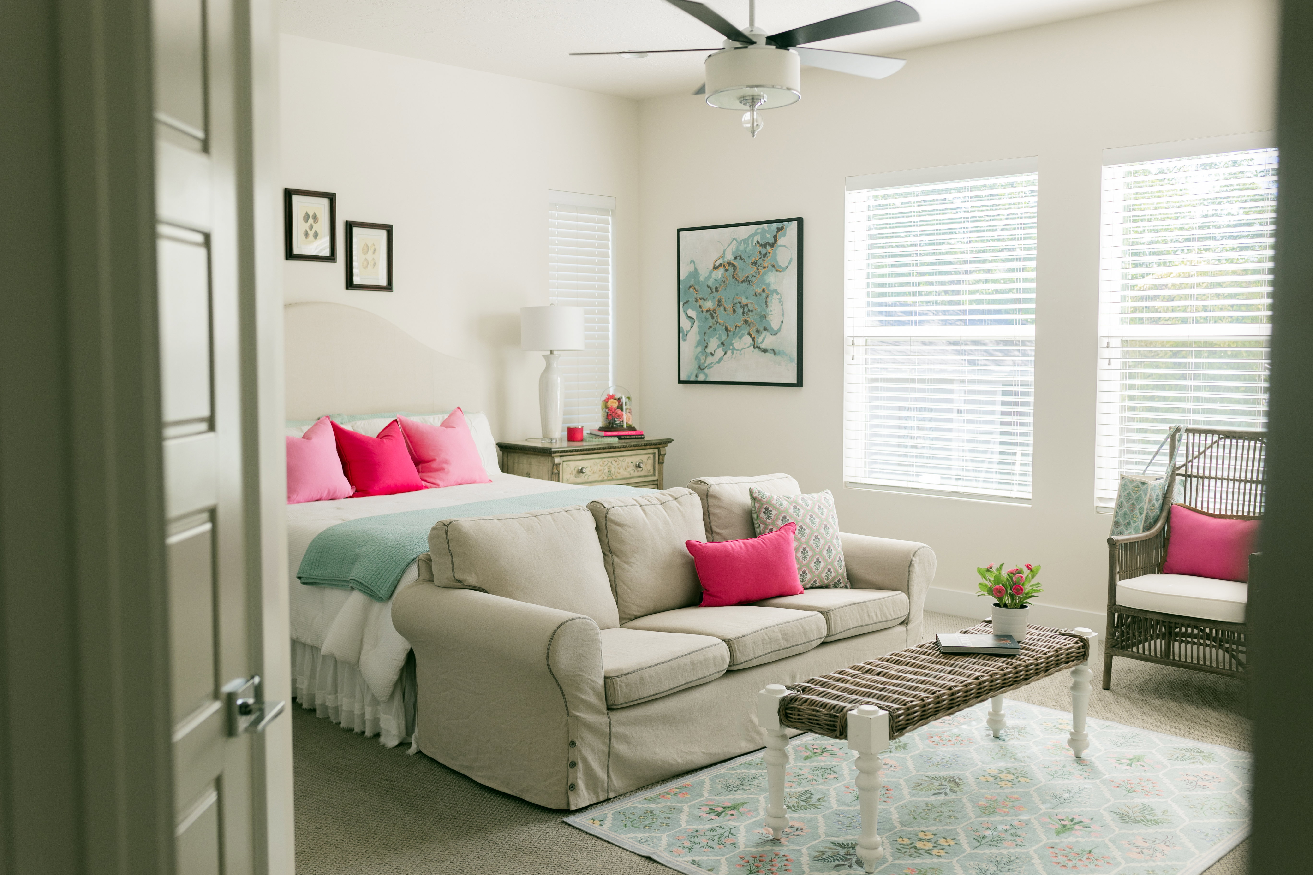 Primary bedroom on main floor. Bright room featuring a ceiling fan, dual windows with blinds, and light-colored walls