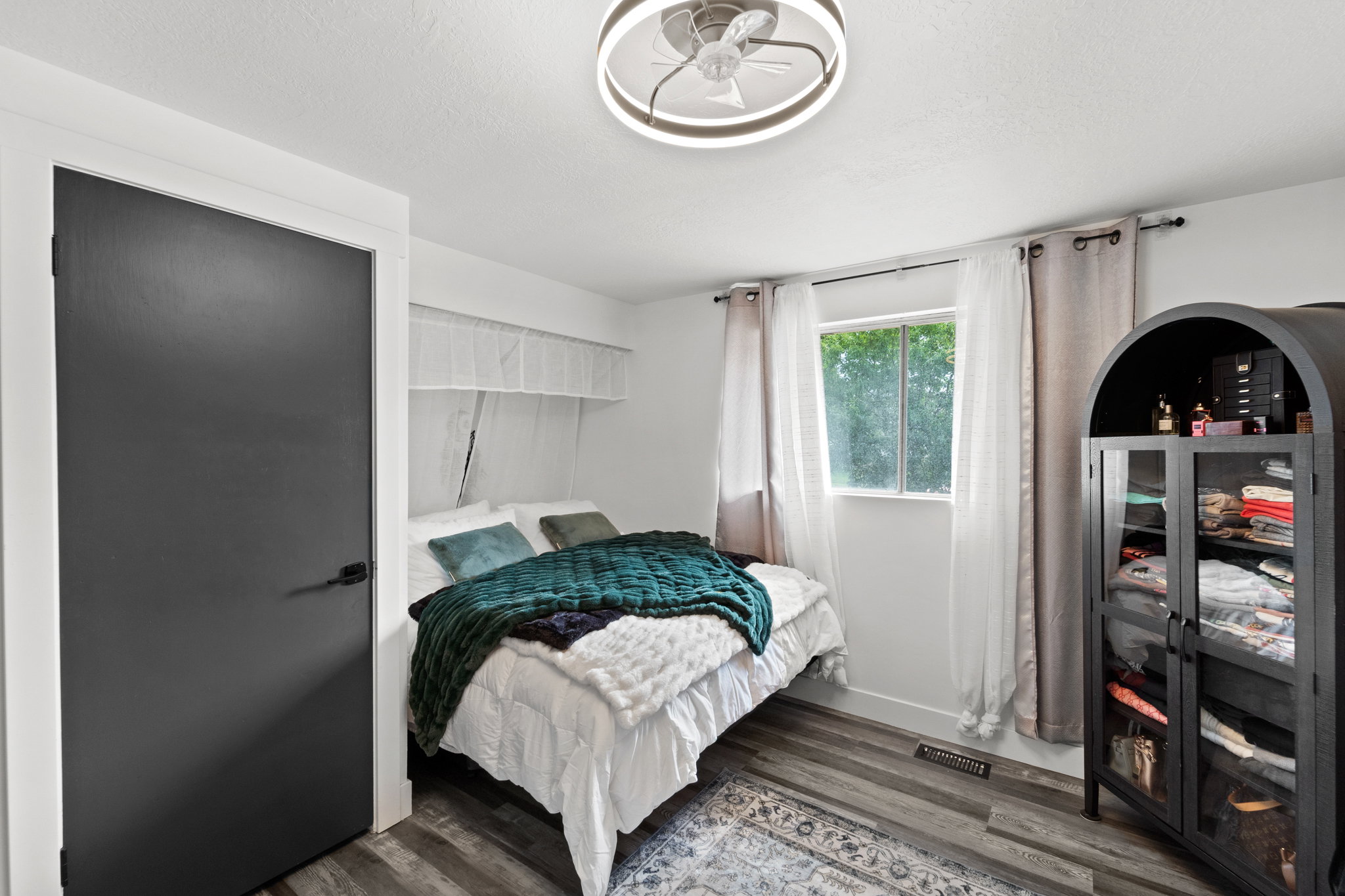 Bedroom featuring wood-finish flooring, a contemporary ceiling fan, and a window with natural light