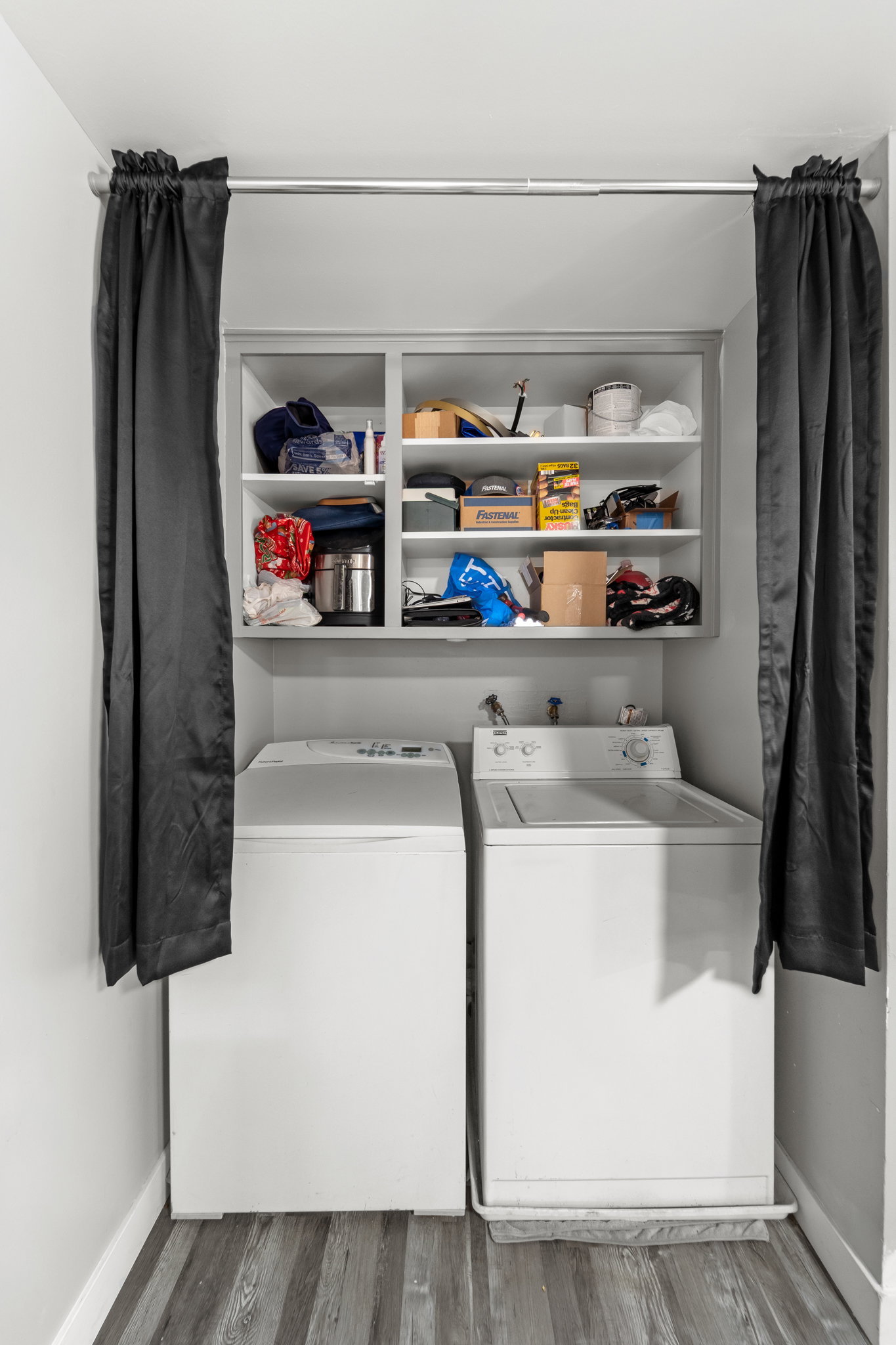 Dedicated laundry area featuring wood-finish flooring and an upper storage cabinet