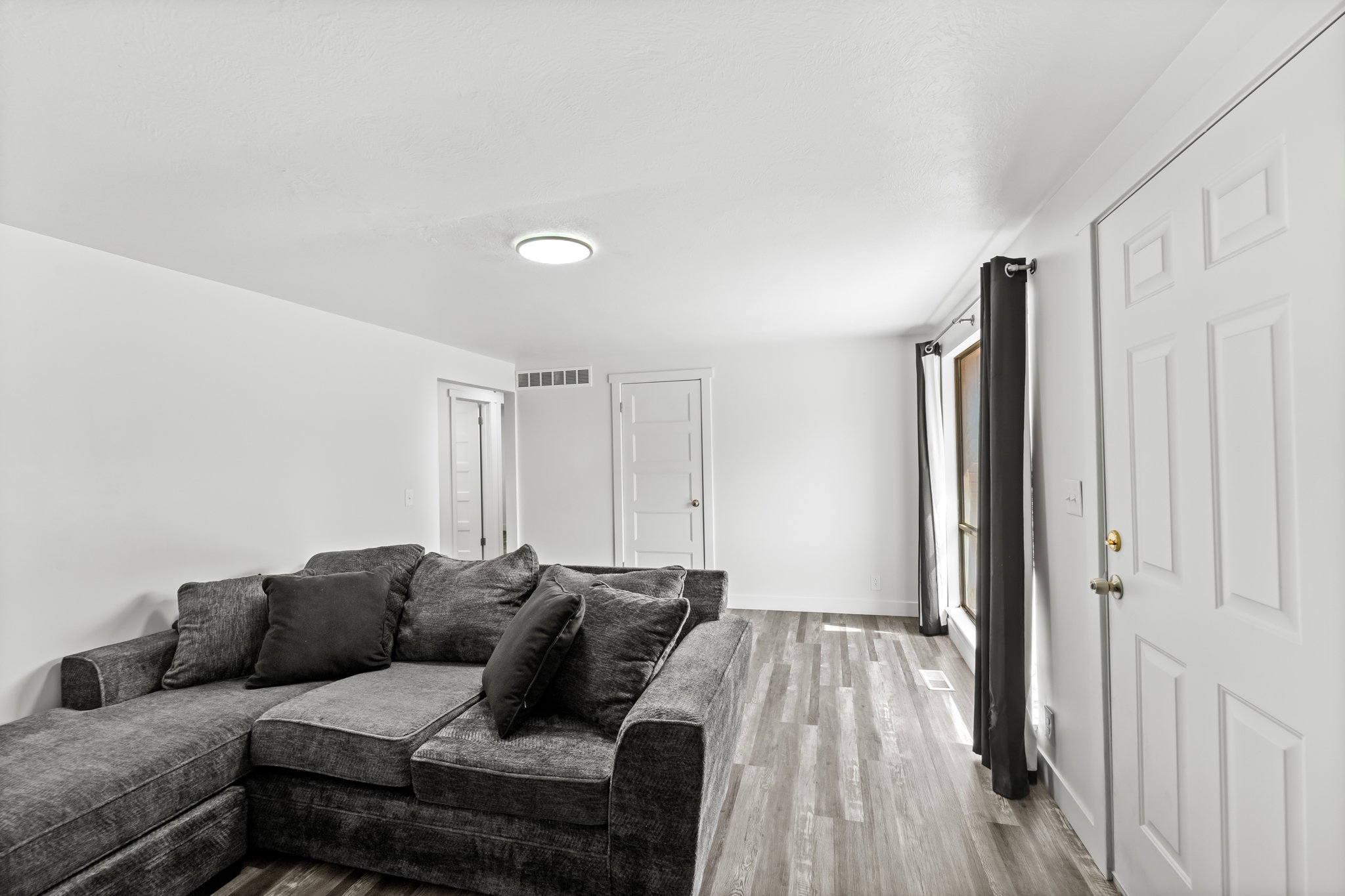 Spacious room featuring wood-finish flooring, white walls, and a recessed ceiling light