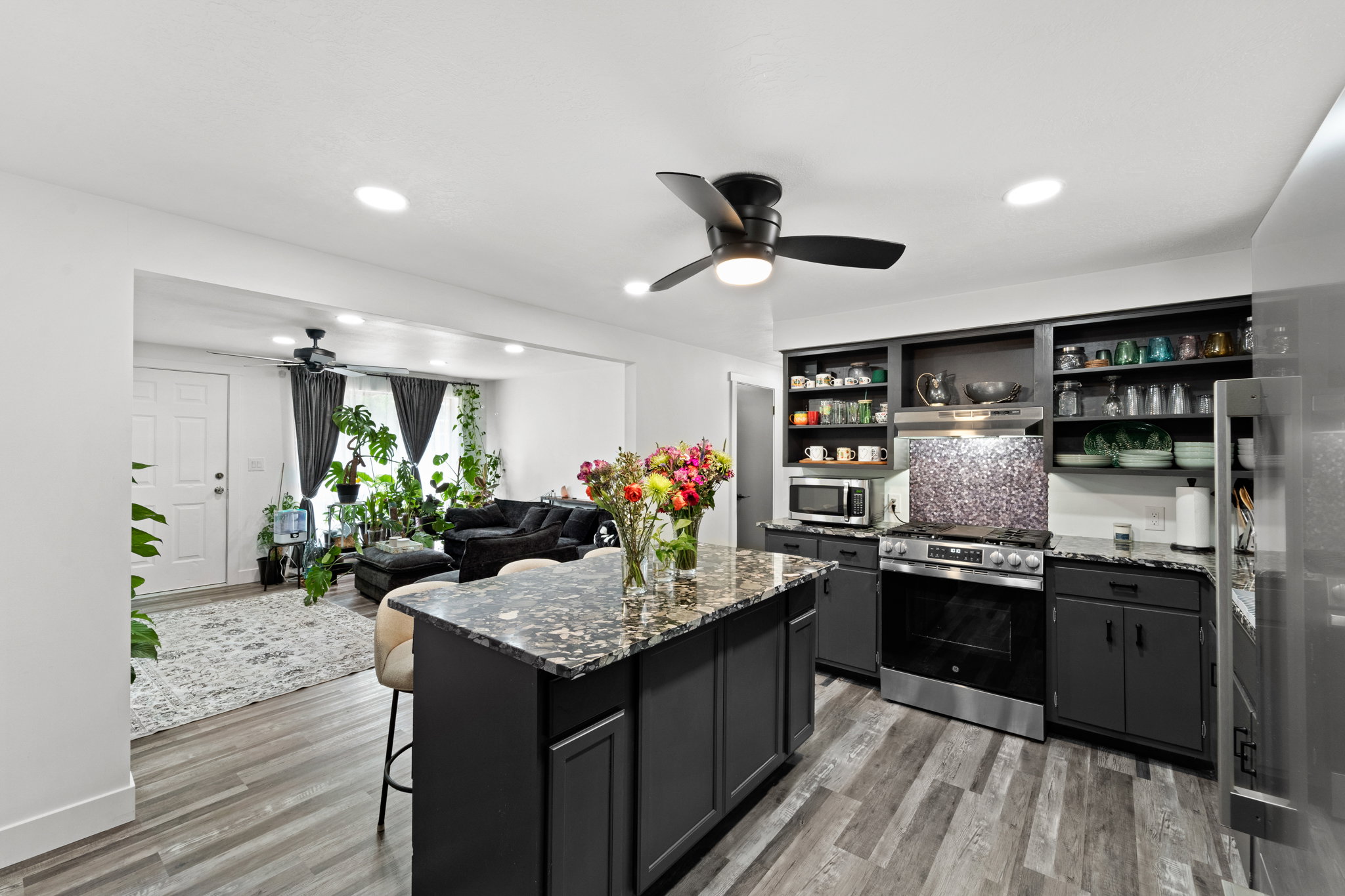 Kitchen featuring a central island with a granite-style countertop, stainless steel appliances, dark cabinetry, and wood-finish flooring