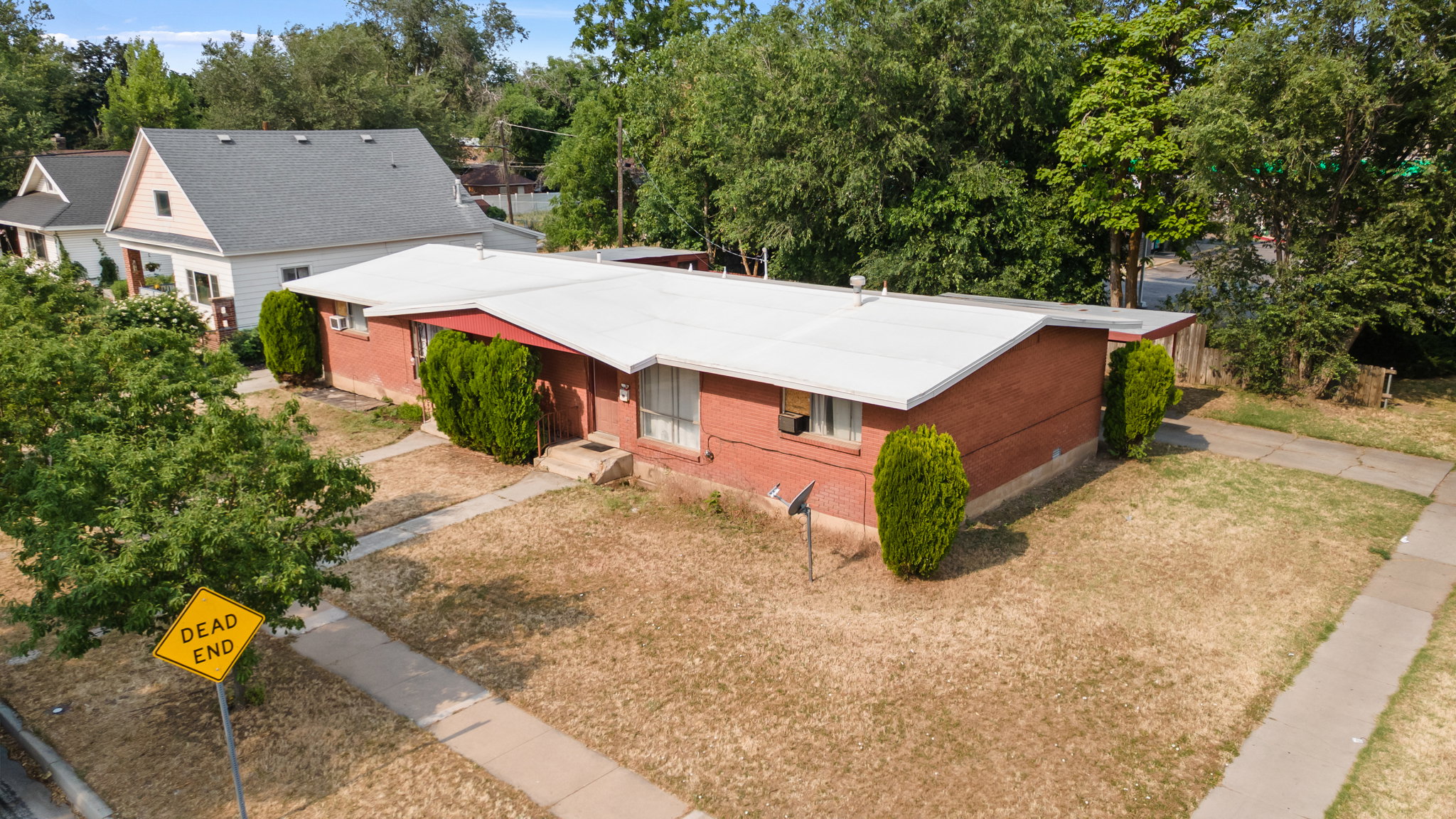 Brick exterior home with a white flat roof and an attached carport