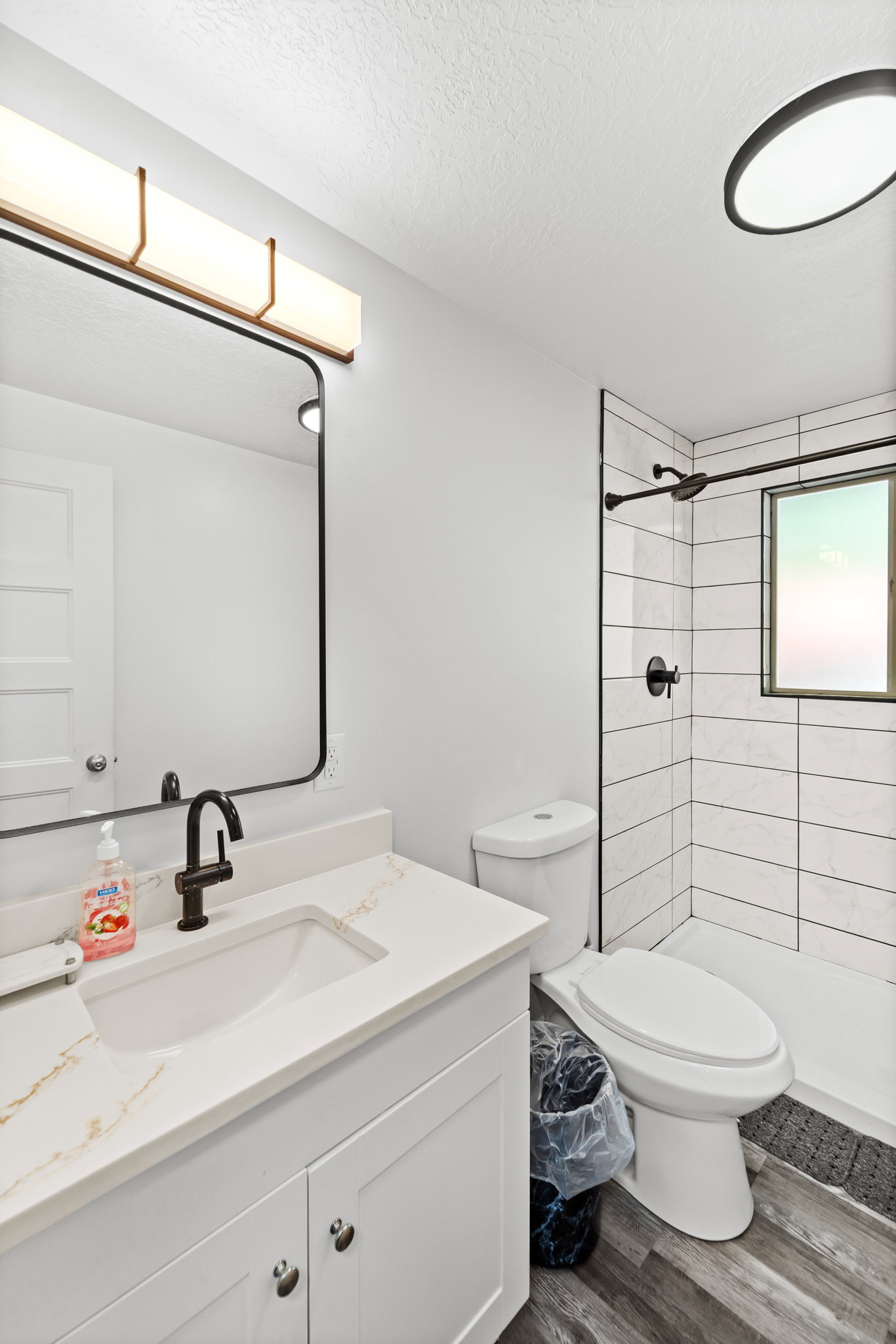 Modern bathroom featuring a white vanity with a quartz-look countertop, integrated sink, and matte black faucet