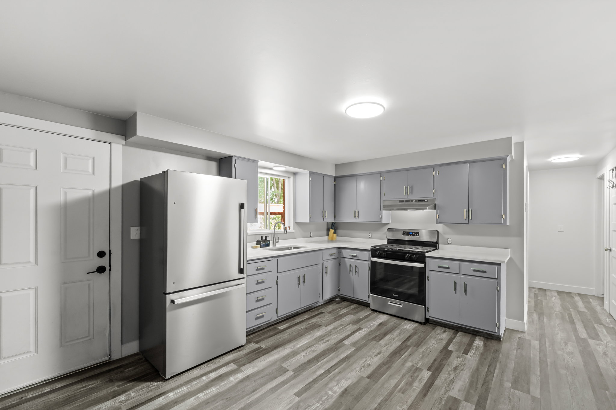 Kitchen featuring stainless steel appliances, gray cabinetry, white countertops, and wood-finish flooring