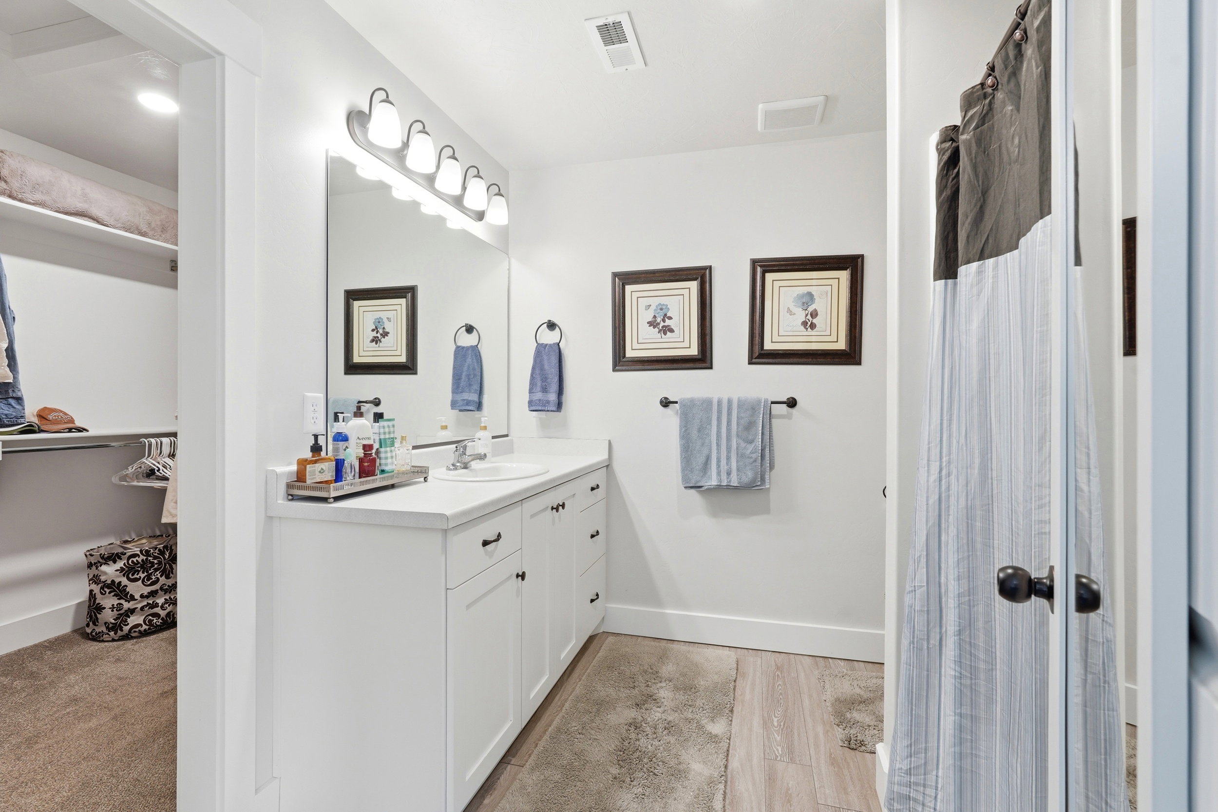 Bathroom featuring a single vanity with a white countertop, undermount sink, and matte black hardware