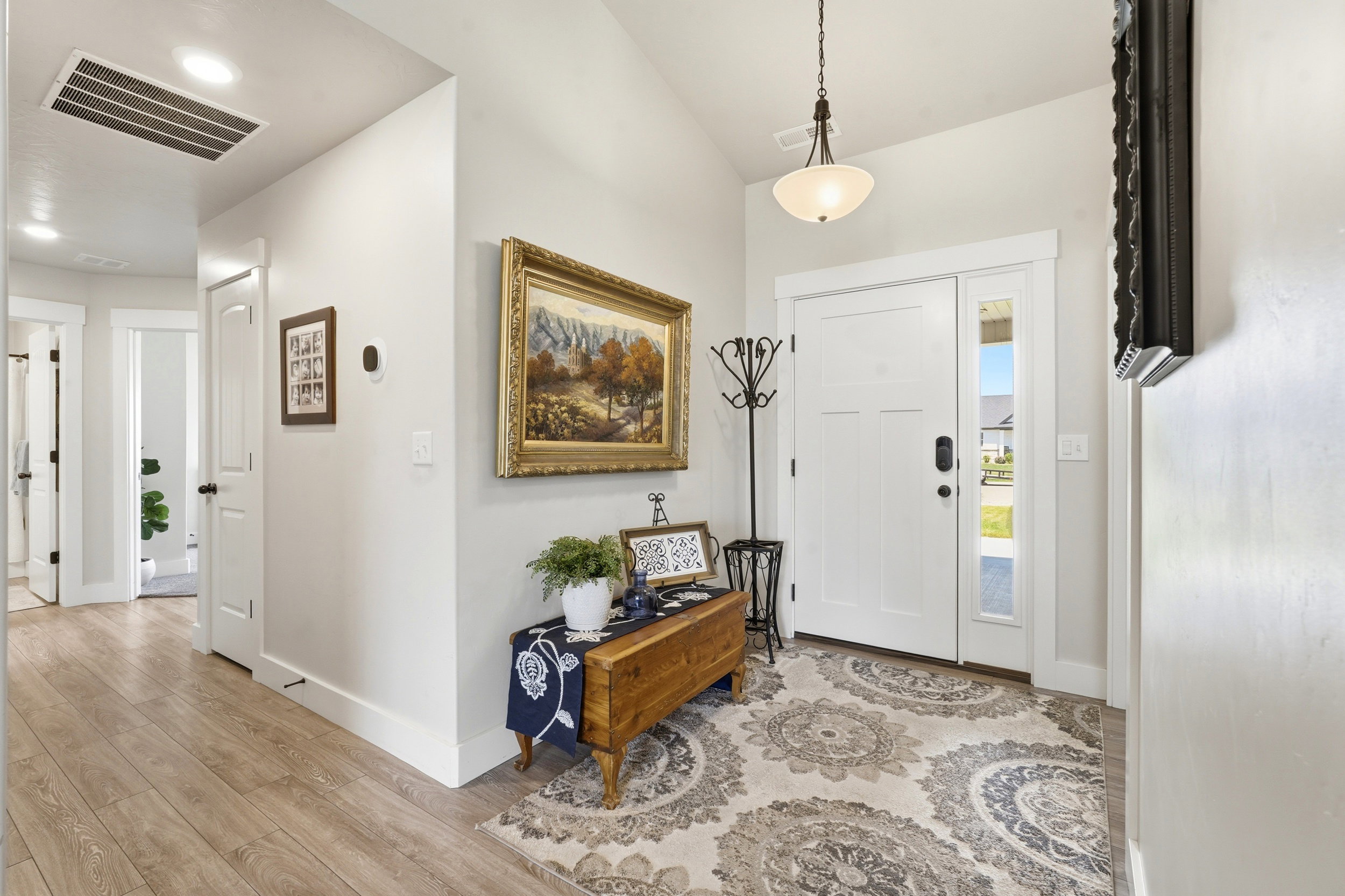 Foyer featuring a paneled entry door with a sidelight, vaulted ceilings, pendant lighting, and wood-finish flooring