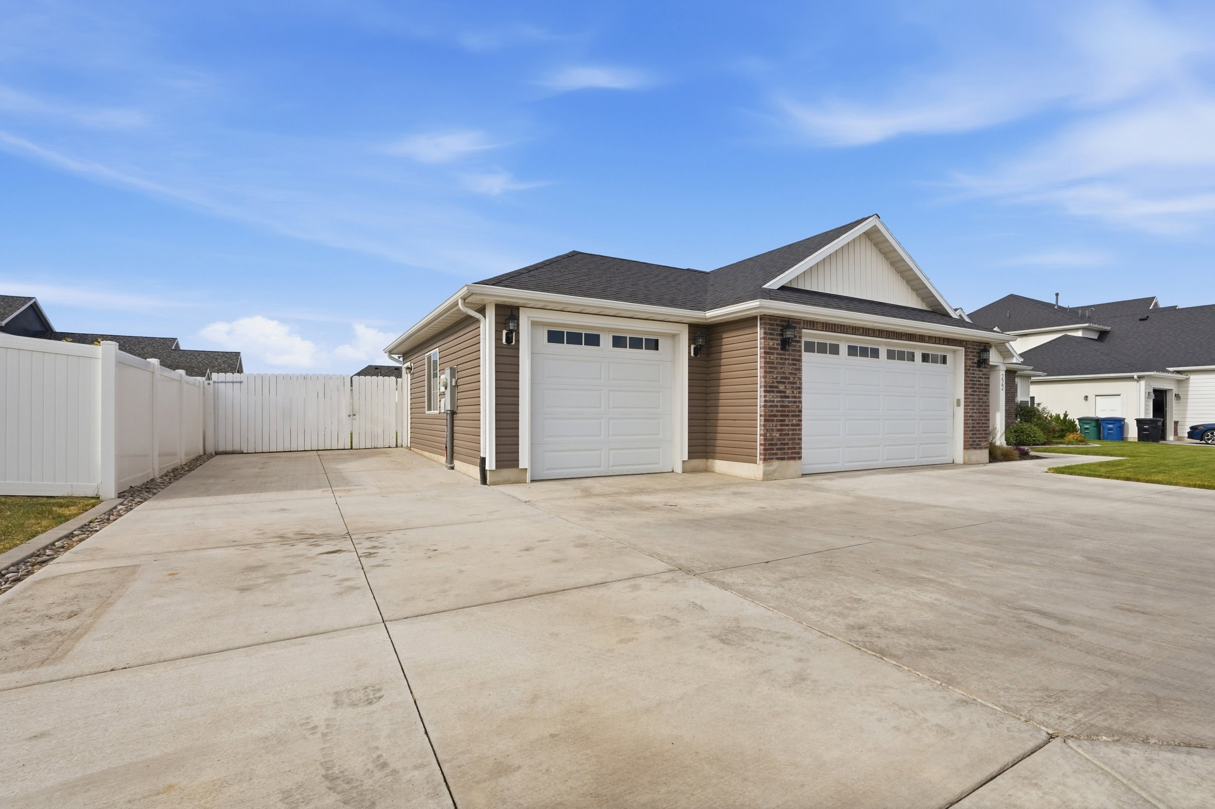 Expansive concrete driveway servicing a two-car garage with white paneled doors