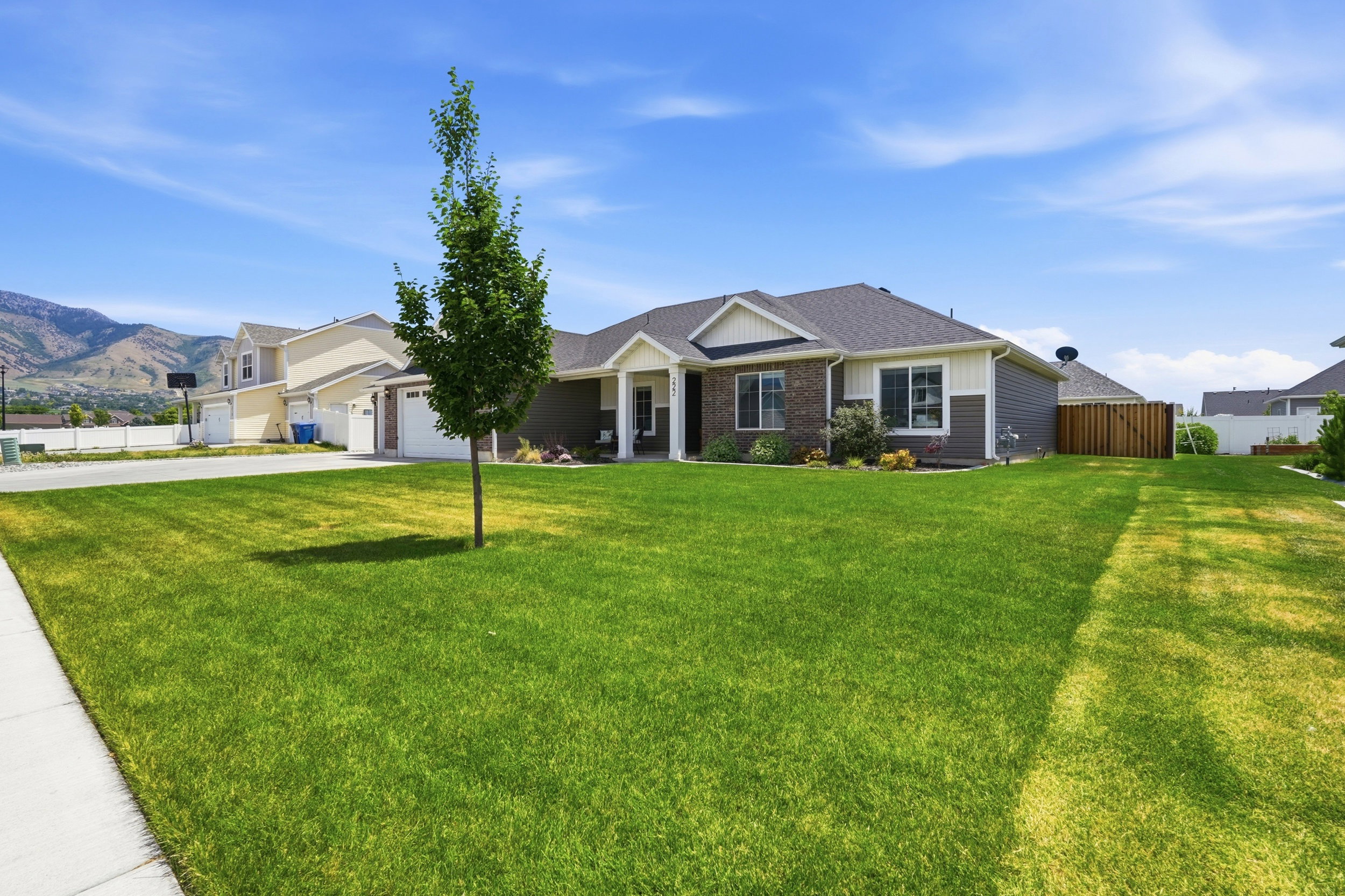 Ranch-style exterior featuring a dark gray siding, brick accents, white trim, and a covered front porch