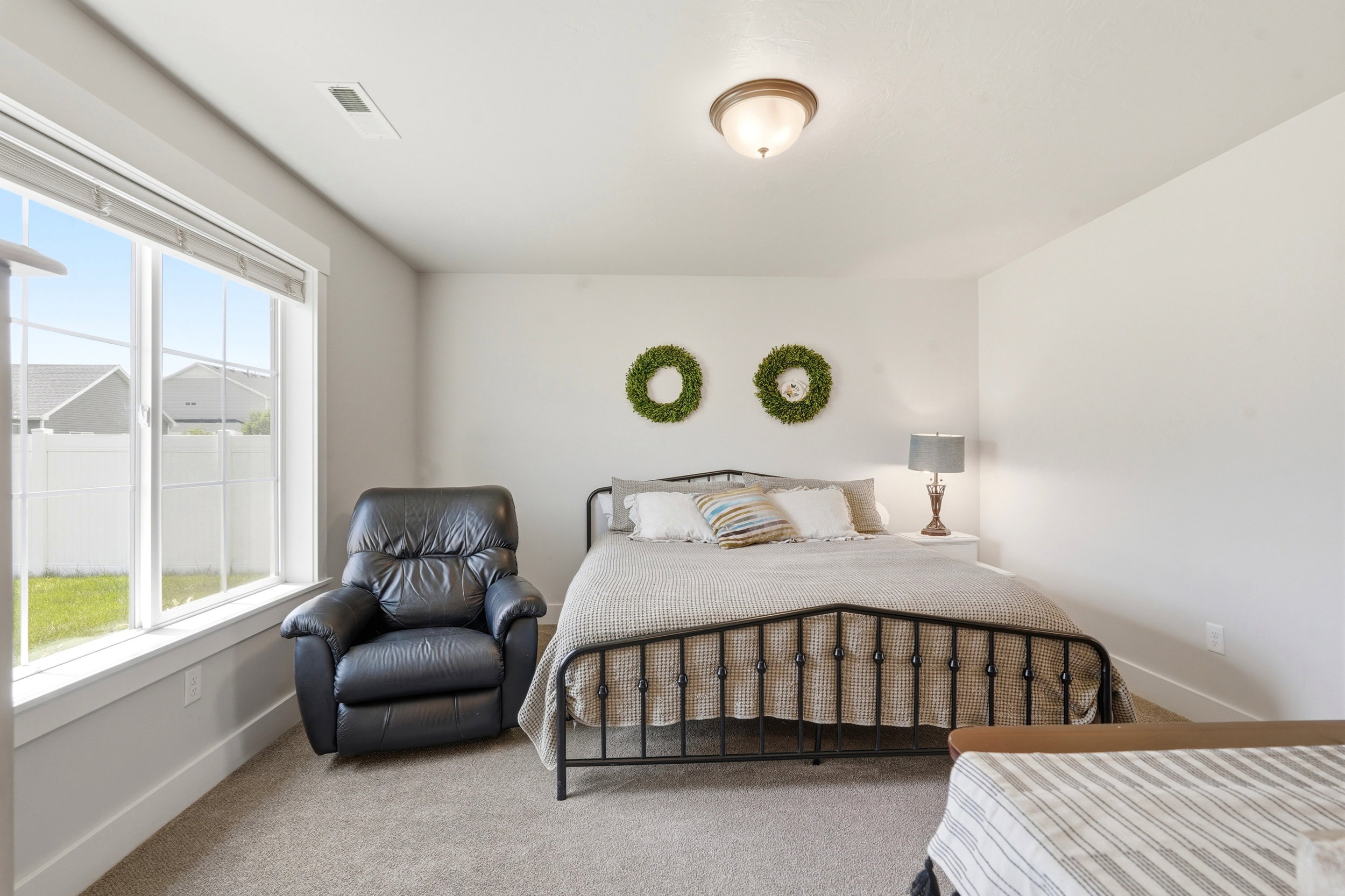 Spacious room featuring light-toned walls, plush carpet flooring, a large window with white trim, and a ceiling-mounted light fixture