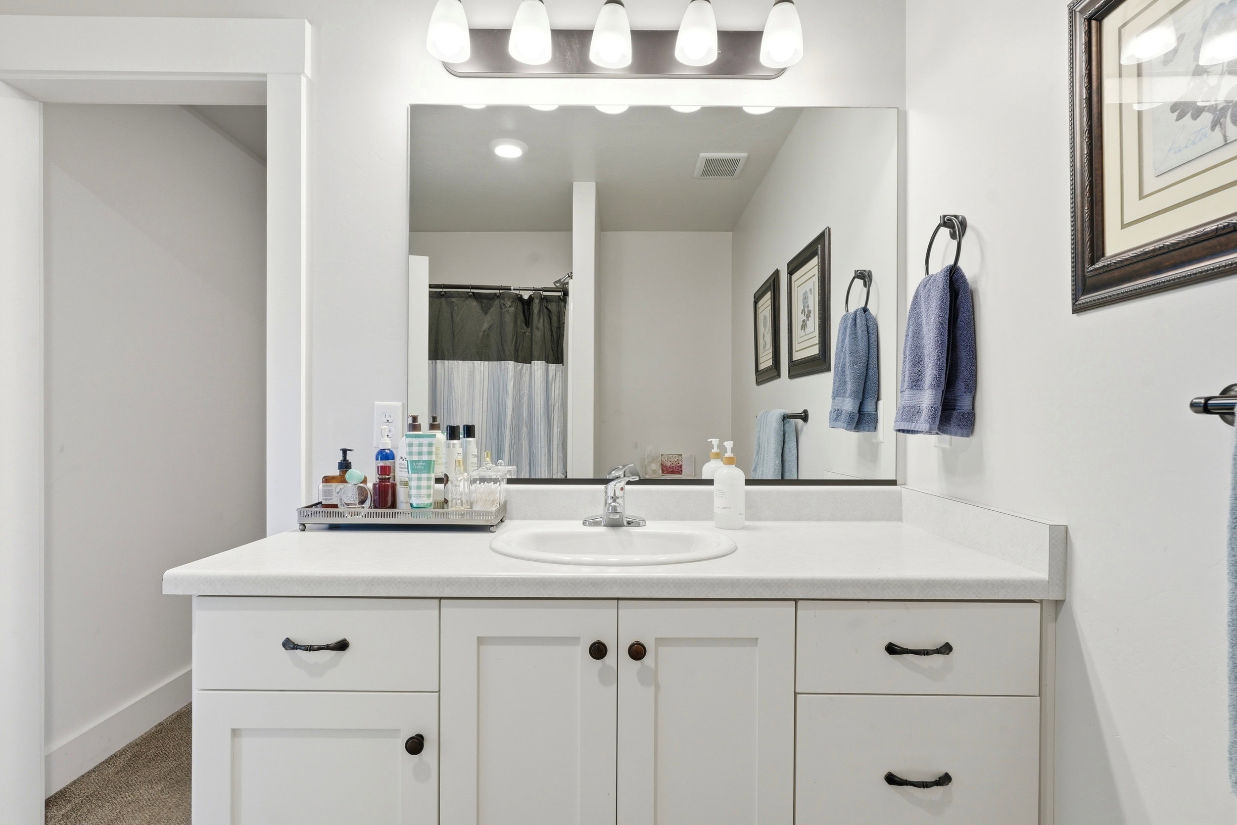 Bathroom vanity featuring a white countertop, an integrated sink, and white cabinetry with dark hardware
