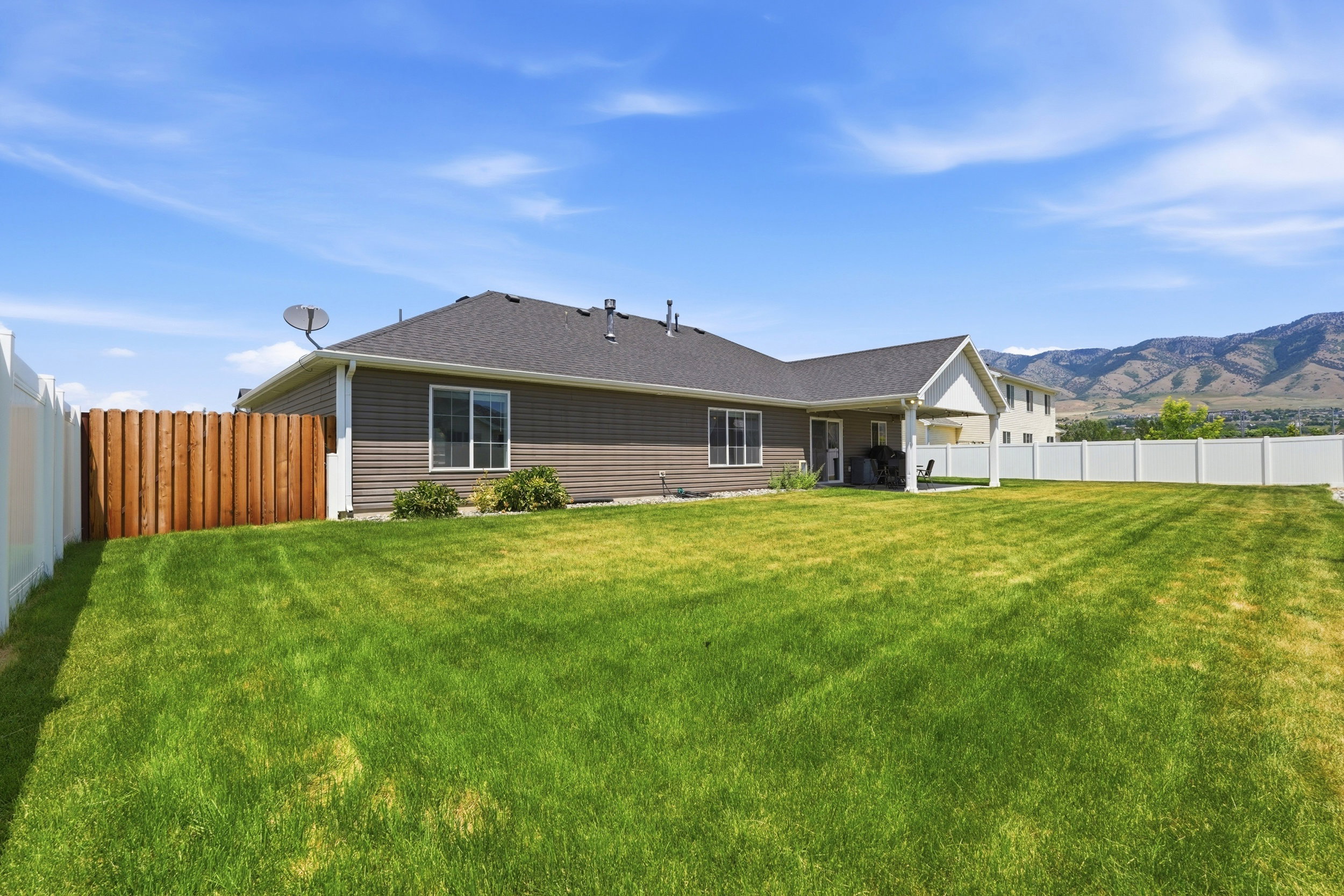 Expansive green lawn surrounds the property, featuring a durable vinyl fence and a partial wood privacy fence