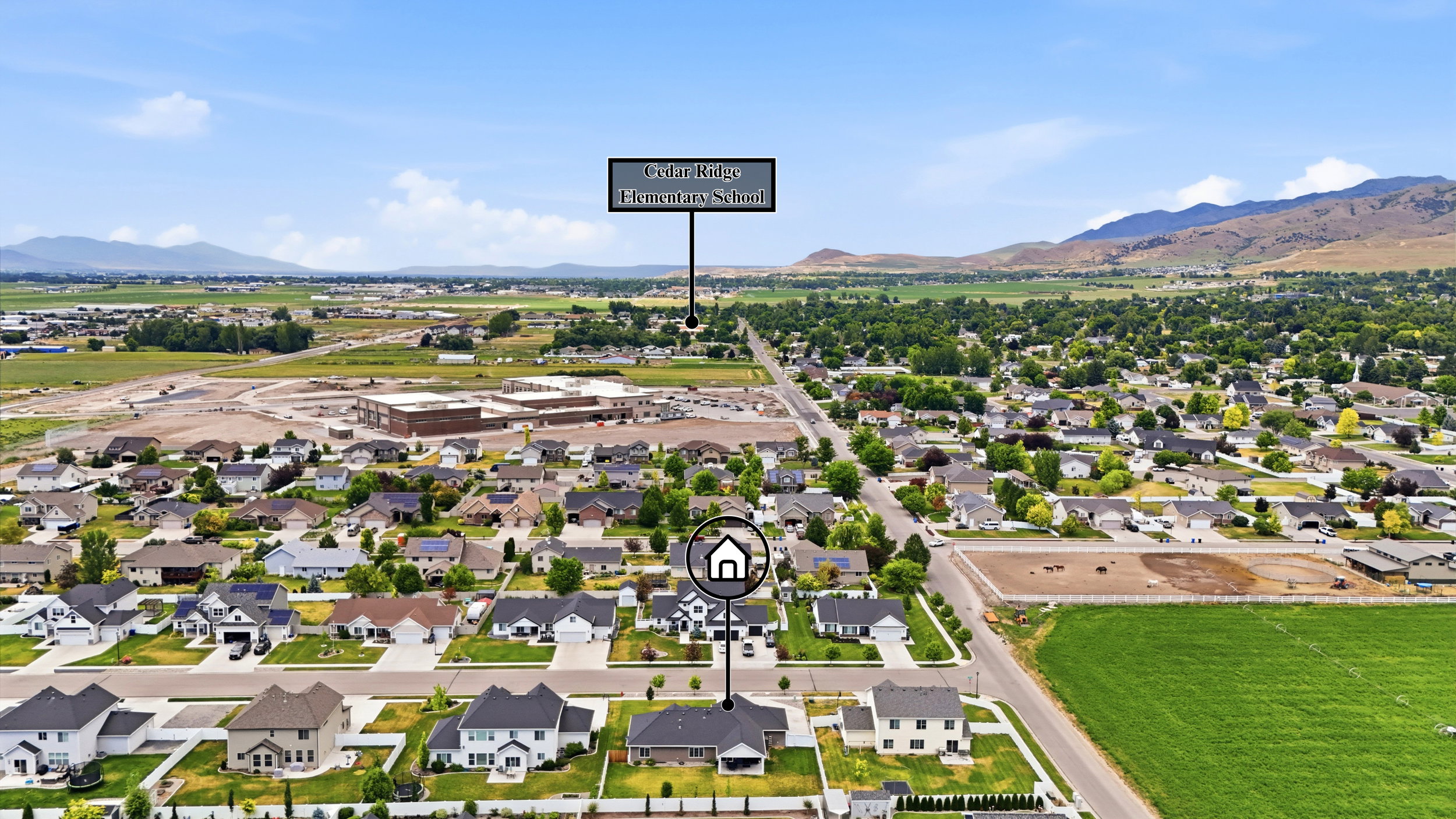 Expansive aerial perspective showcasing a residential neighborhood with surrounding green fields and distant mountains