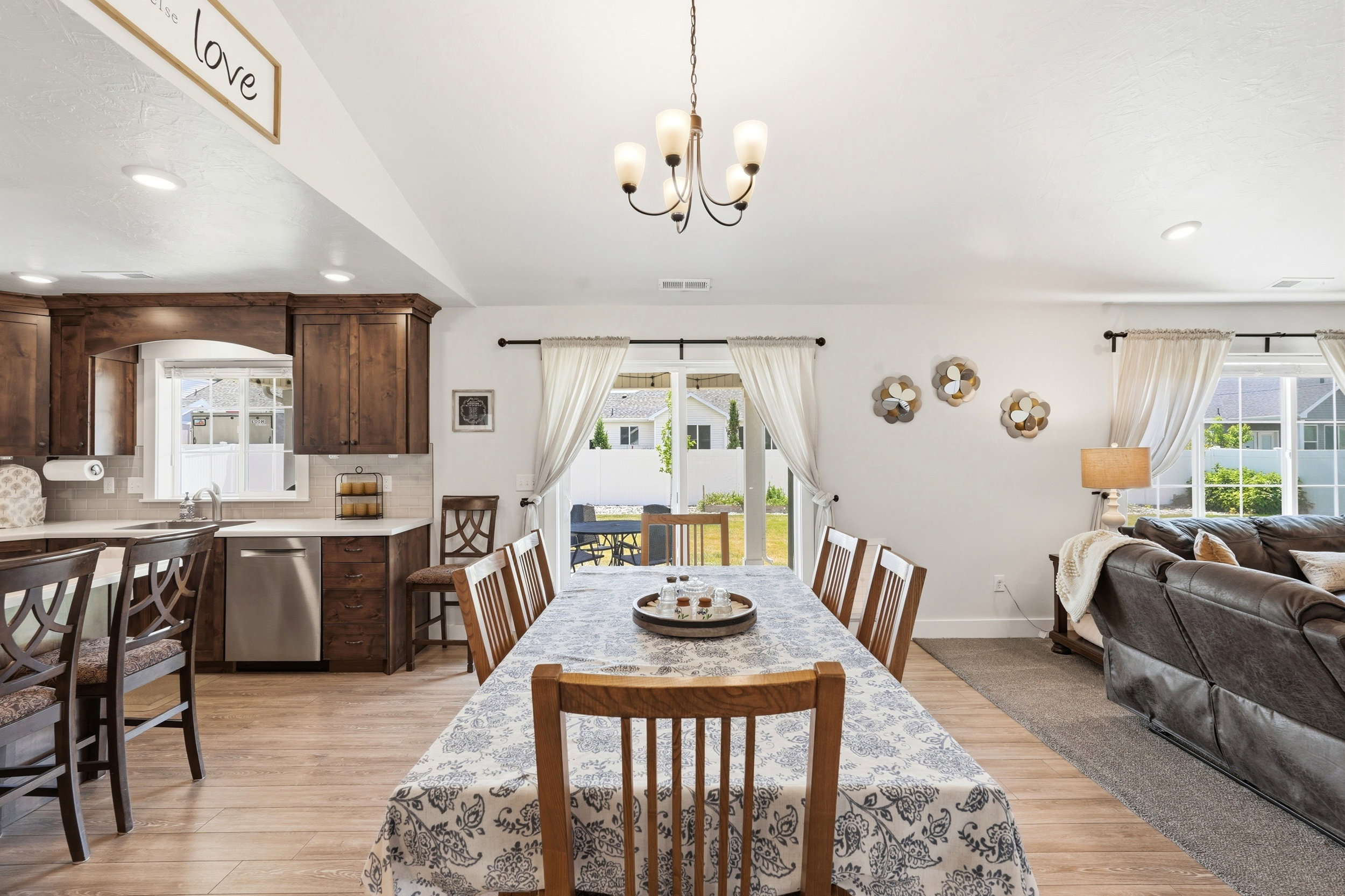 Open concept living area featuring wood-finish flooring, a kitchen with dark wood cabinetry and stainless steel appliances, and a dining area with a chandelier