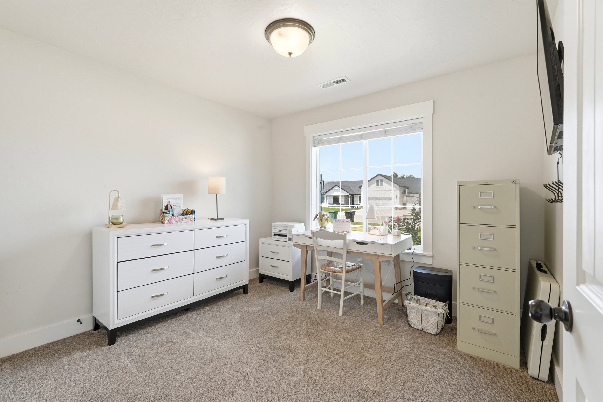 Carpeted room featuring a large window with white trim, a flush-mount ceiling light fixture, and neutral wall tones