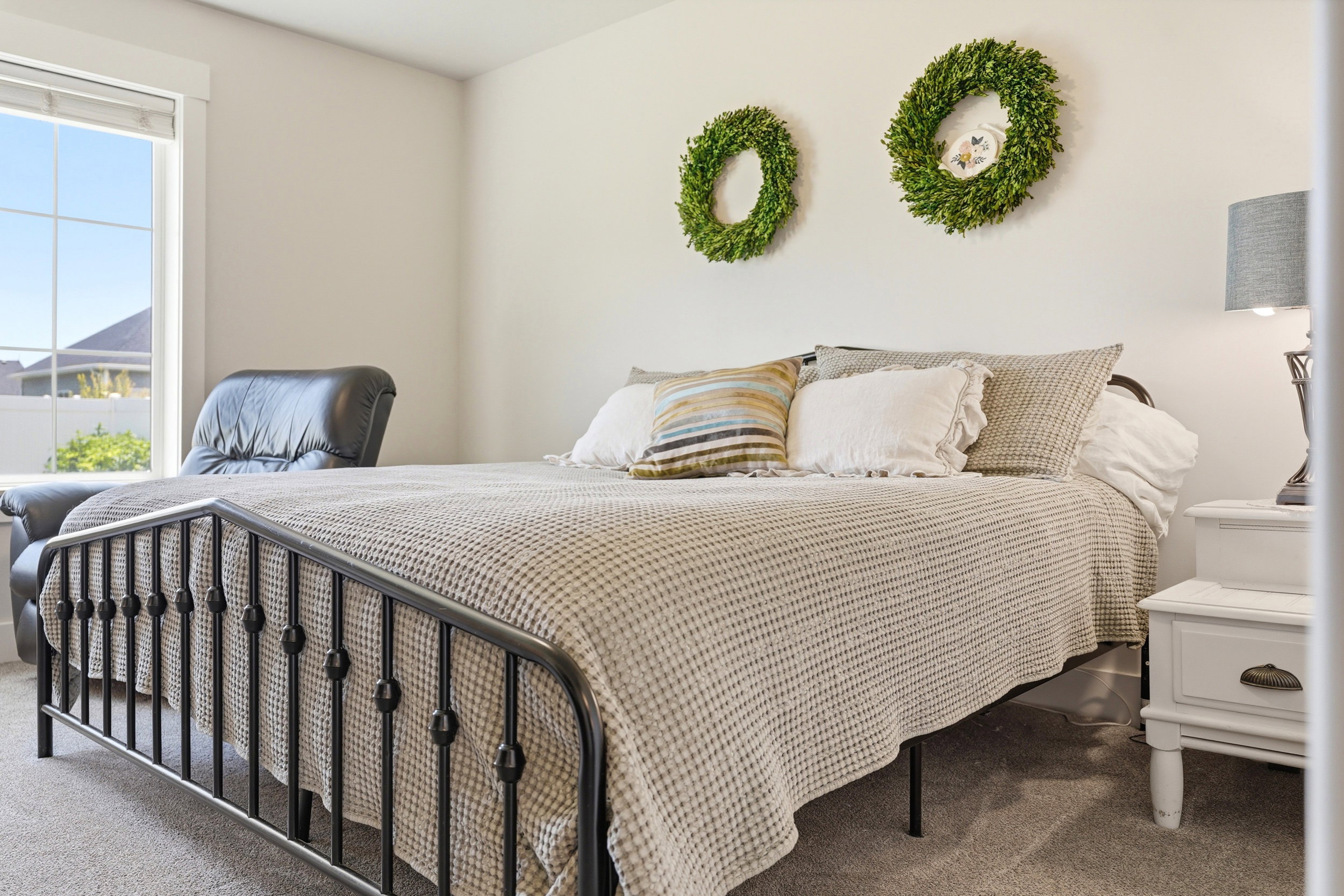 Bedroom featuring light-toned walls, carpet flooring, and a window with white trim