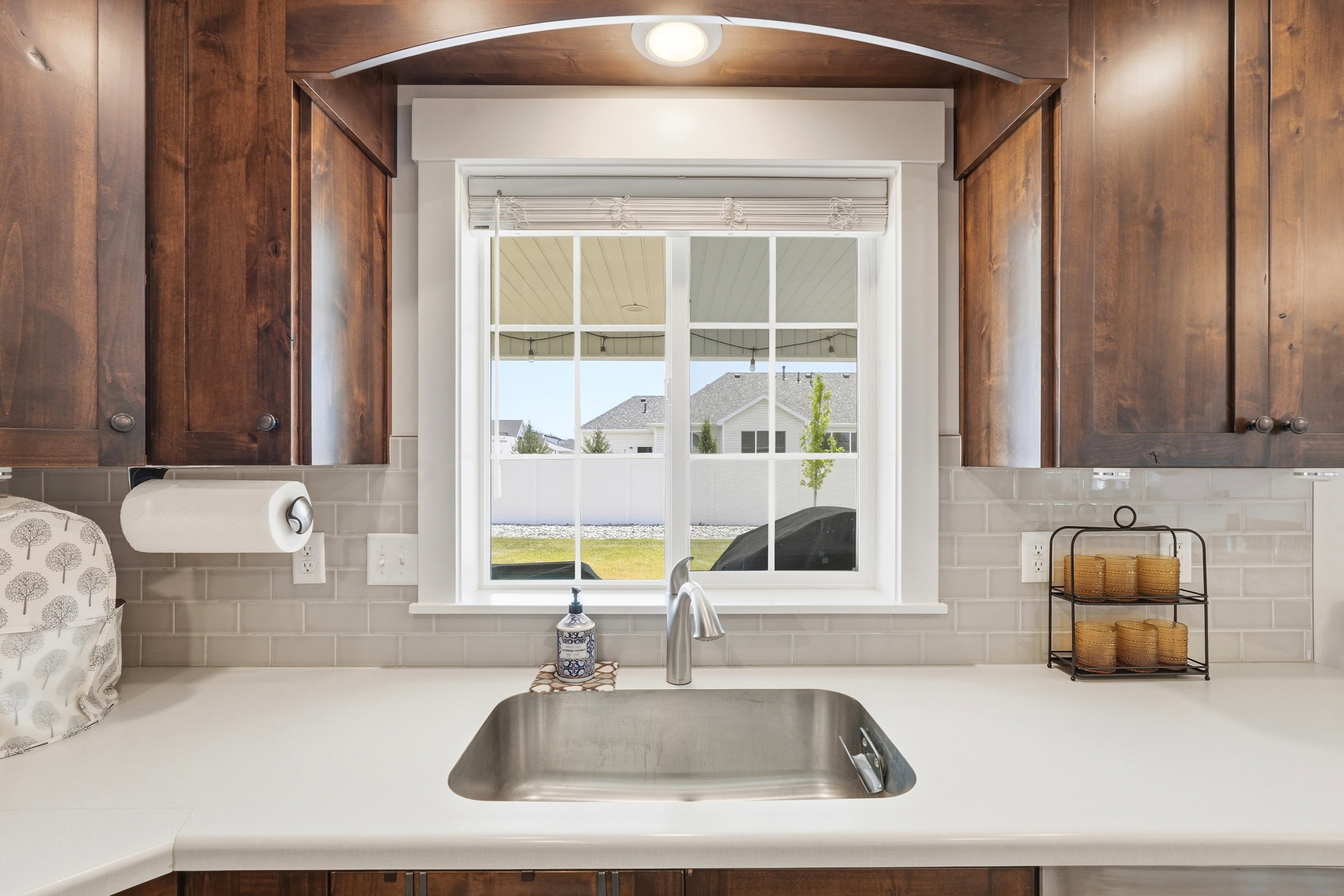 Kitchen sink area featuring a stainless steel undermount sink, a white countertop, and a subway tile backsplash