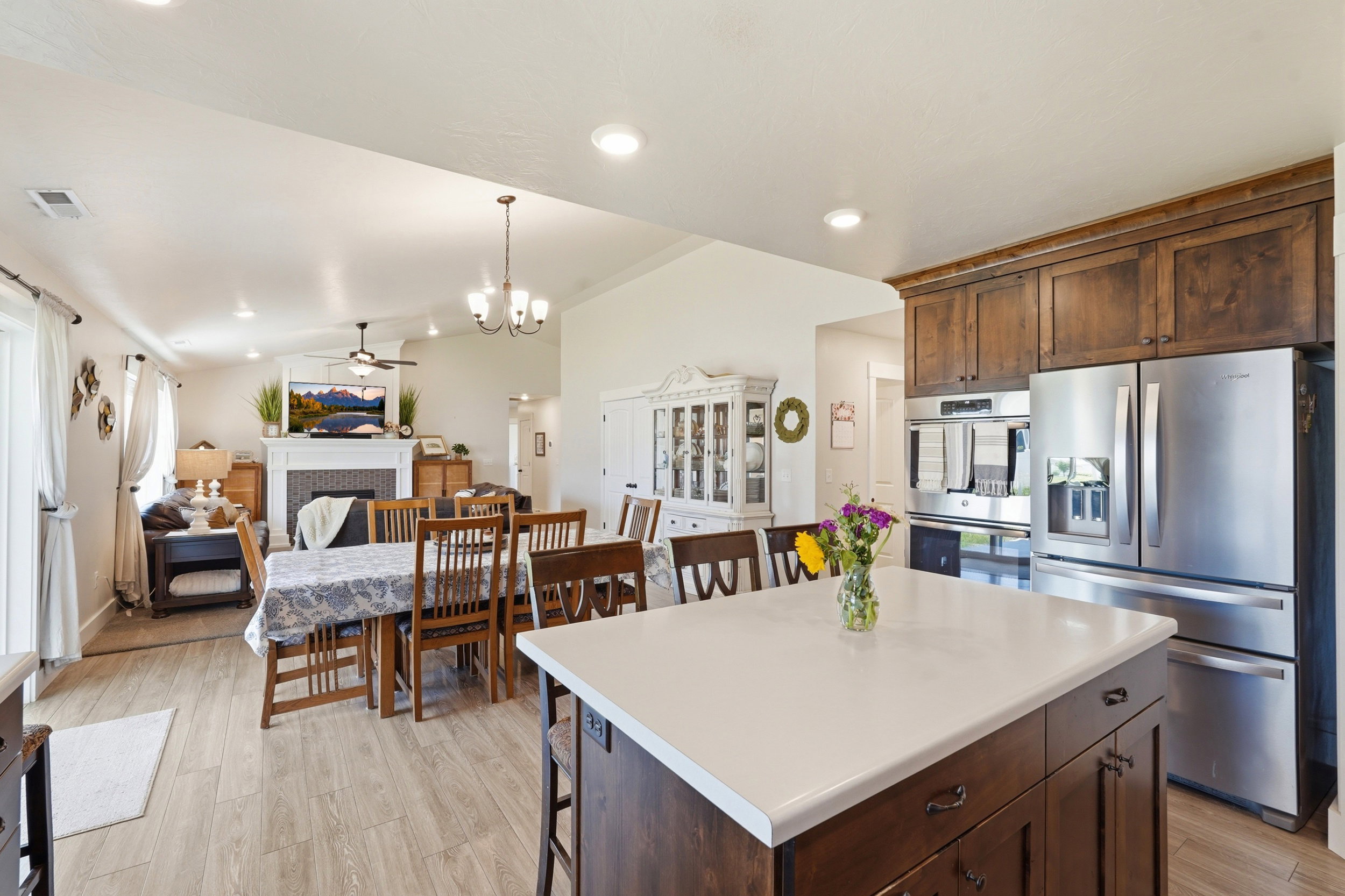 Spacious kitchen island with light-toned countertop, wood-finish cabinetry, stainless steel appliances, recessed lighting, and wood-finish flooring