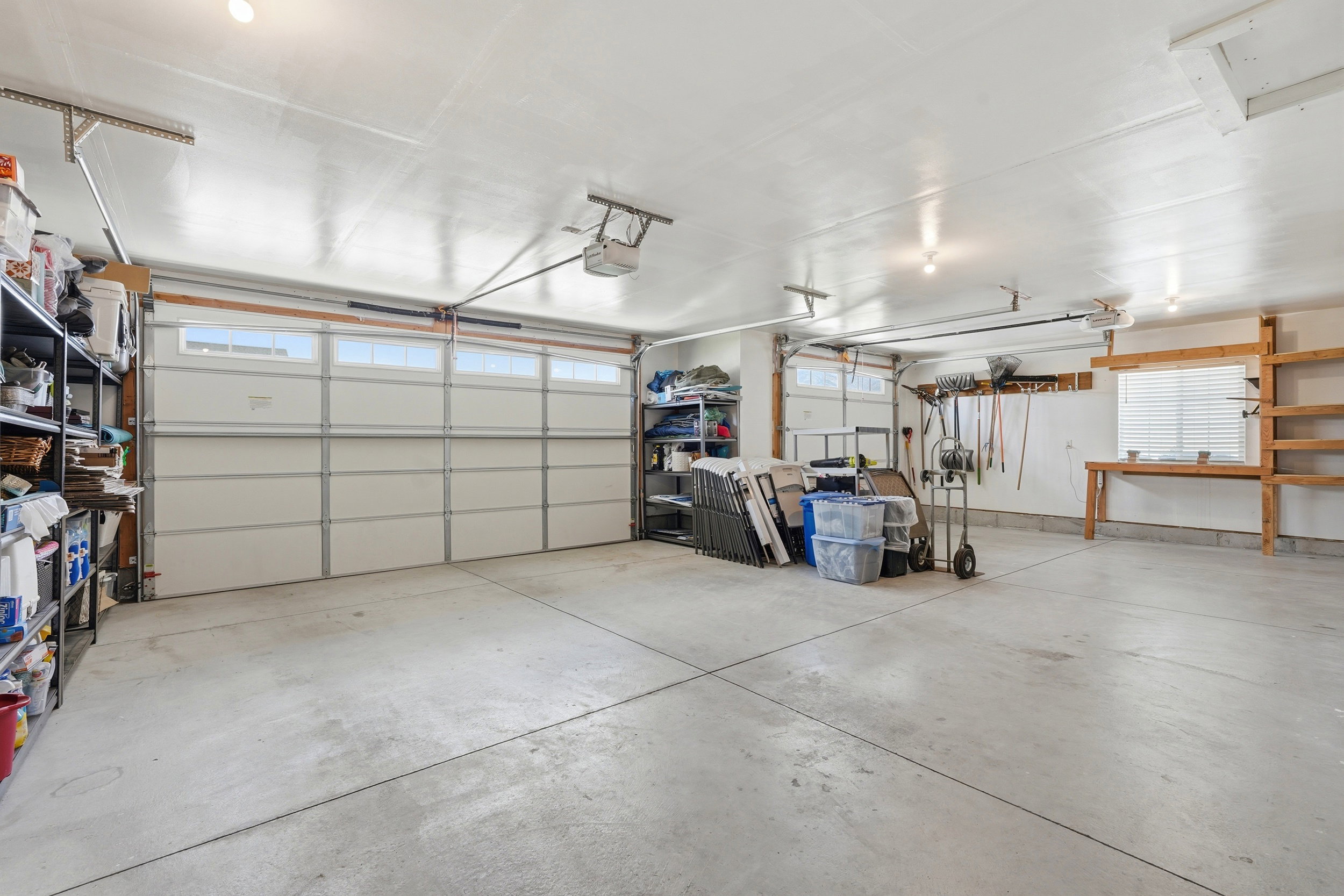 Spacious garage featuring concrete flooring and exposed ceiling beams