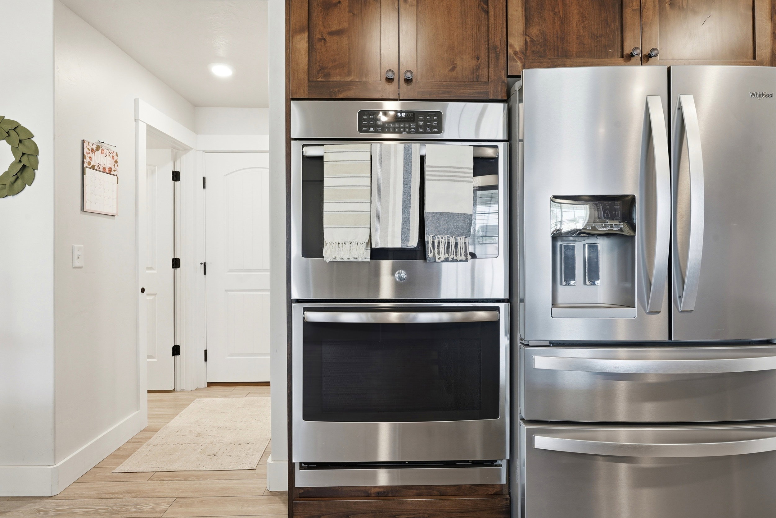 Stainless steel double oven and refrigerator integrated into rich wood cabinetry