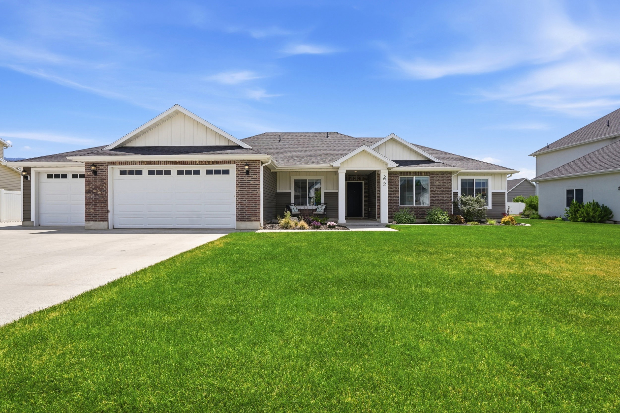 Ranch-style residence featuring a brick and siding exterior, a prominent two-car garage with overhead lighting, an additional single-car garage, and a concrete driveway
