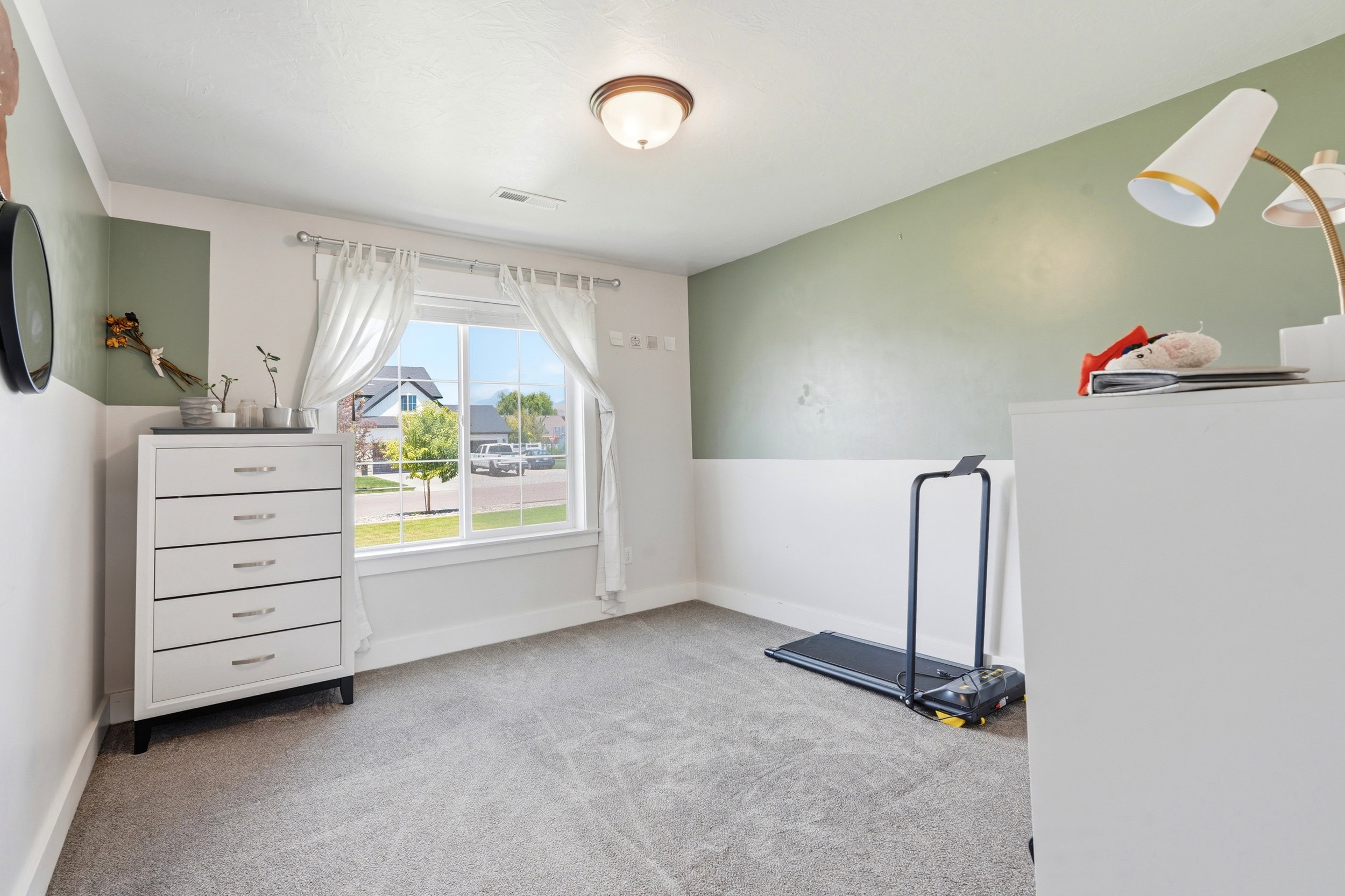 Carpeted interior space with a large window, a two-tone wall treatment, and a flush-mount ceiling light fixture