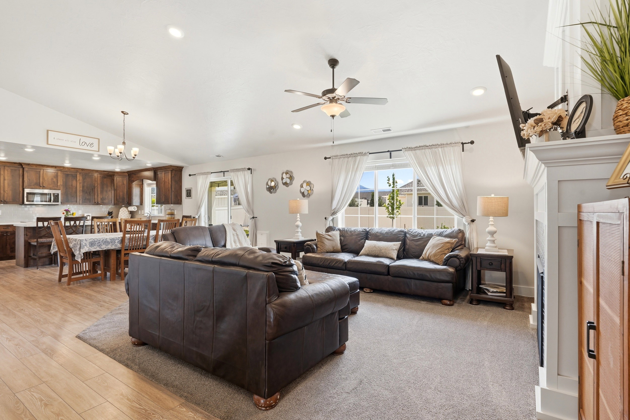 Spacious open-concept living area featuring vaulted ceilings, recessed lighting, and wood-finish flooring