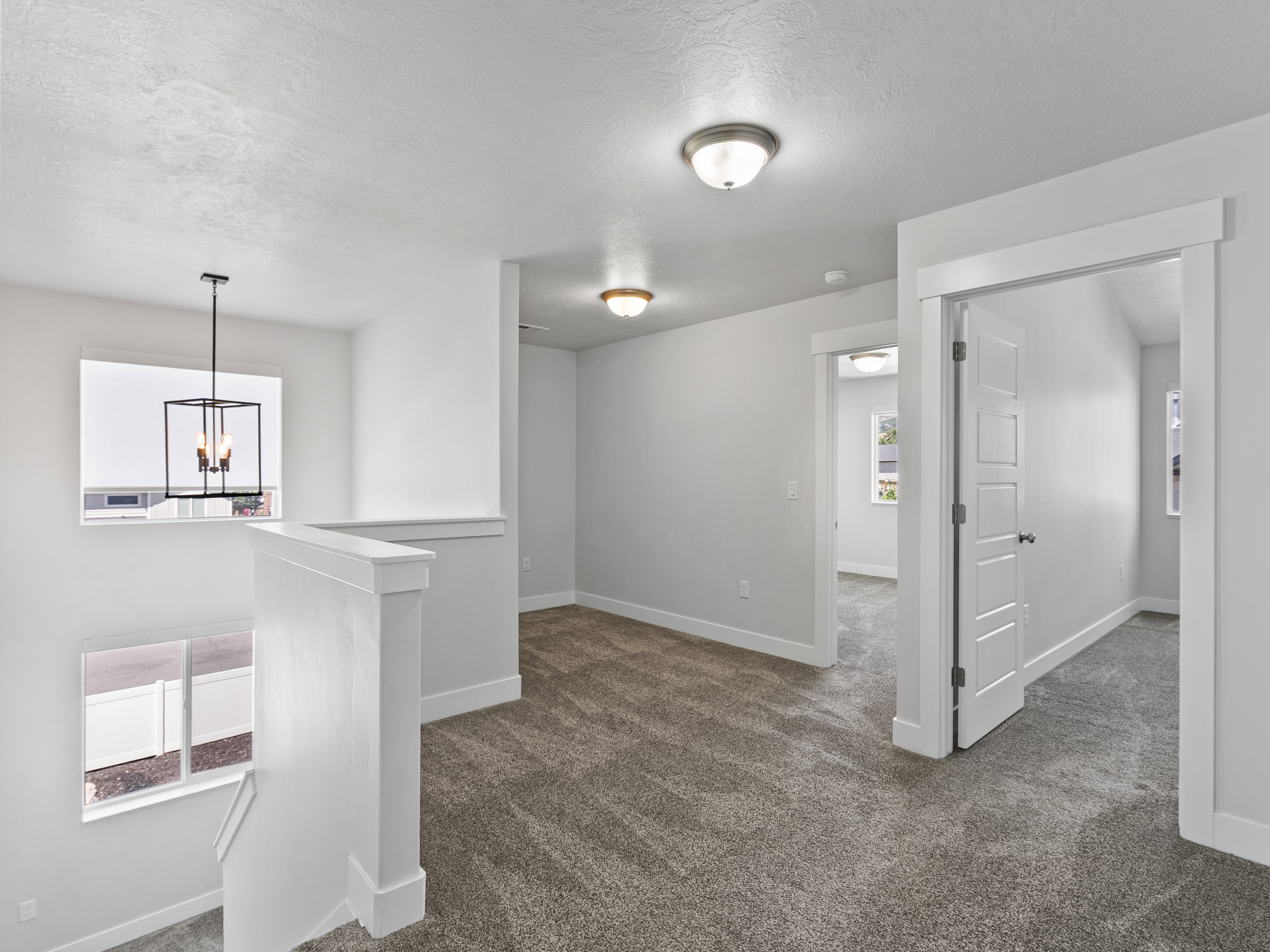 Carpeted loft area featuring white walls, white trim, and white paneled doors