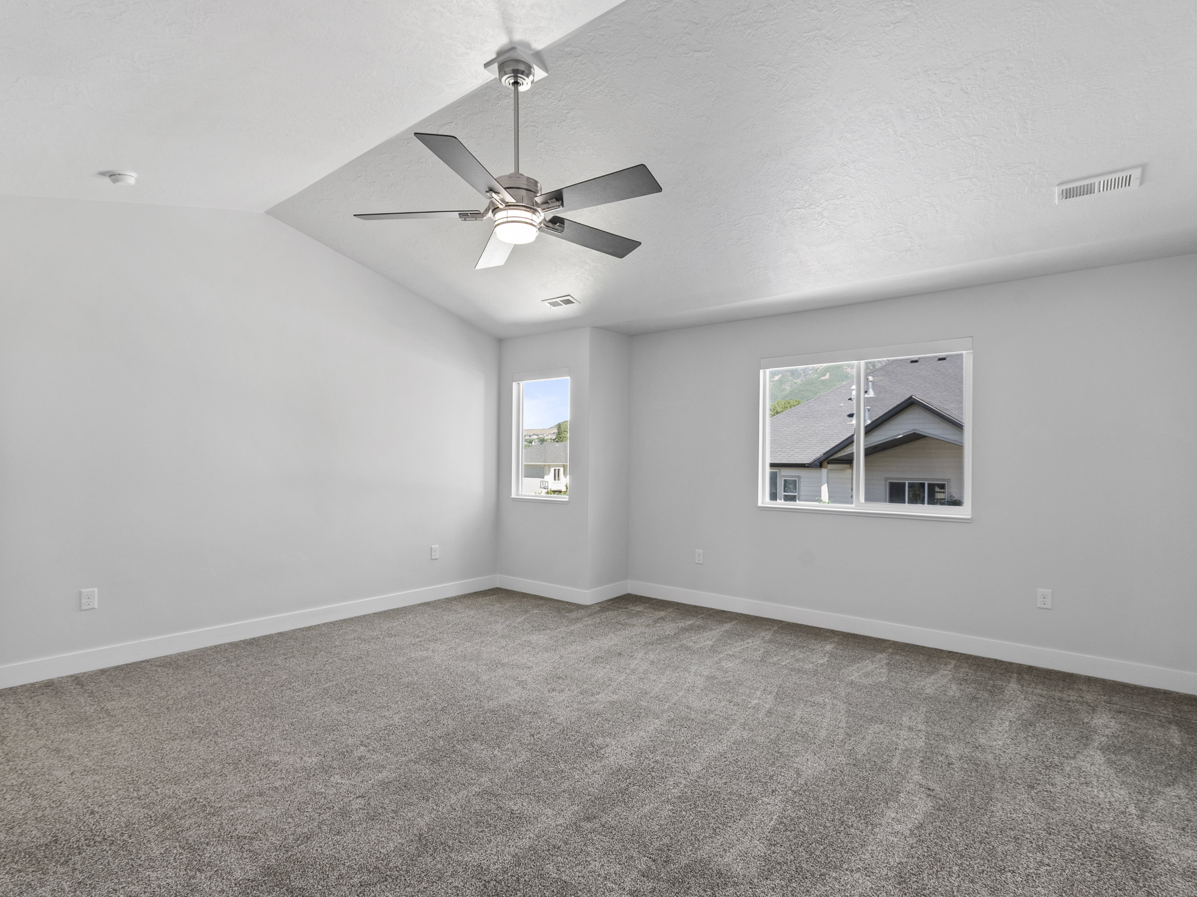 Spacious room with vaulted ceiling and a contemporary ceiling fan