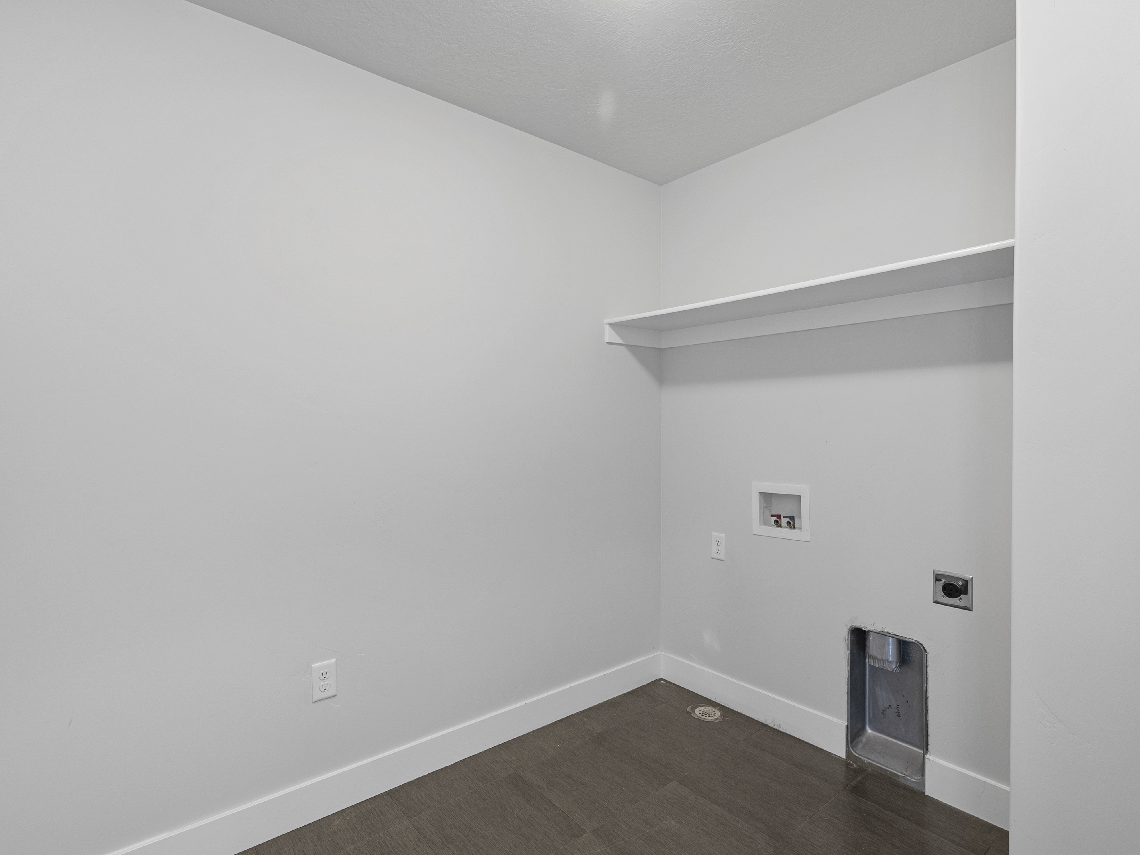 Dedicated utility space featuring a built-in shelf, wood-finish flooring, white baseboards, and essential hookups