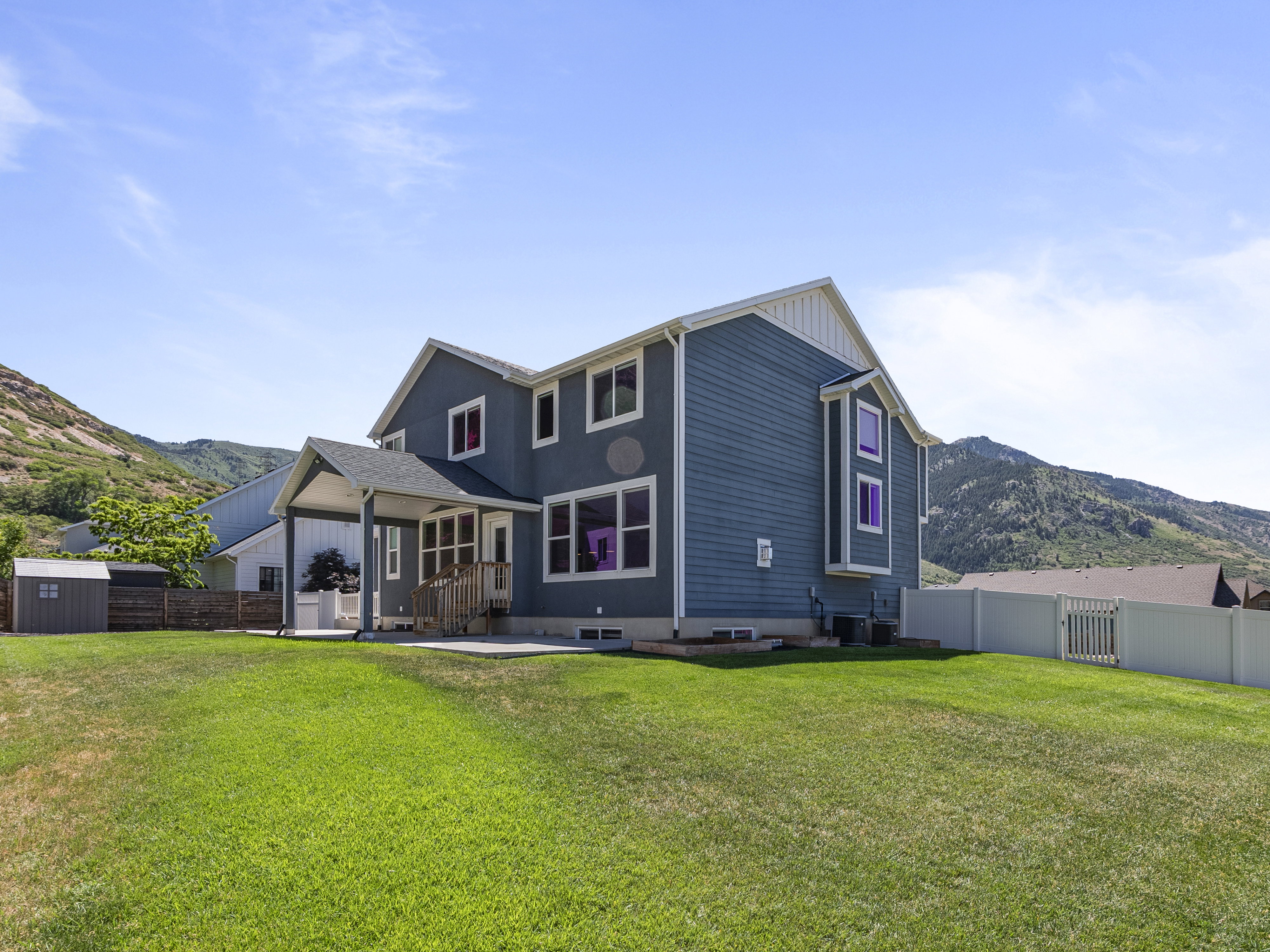 Expansive green lawn with a two-story residence featuring blue siding and white trim