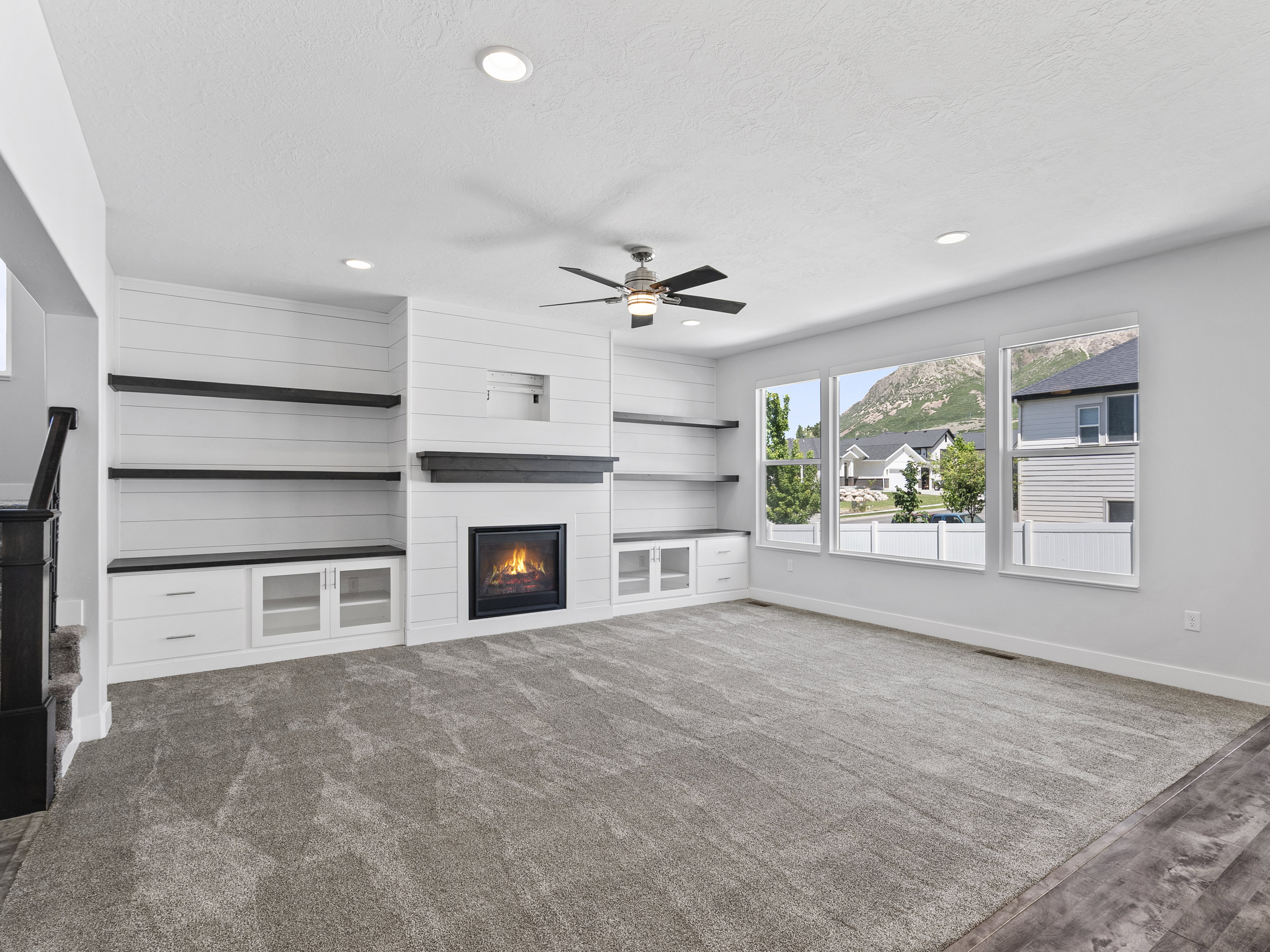 Living area featuring a modern fireplace with a dark wood mantel, flanked by built-in shelving and cabinetry