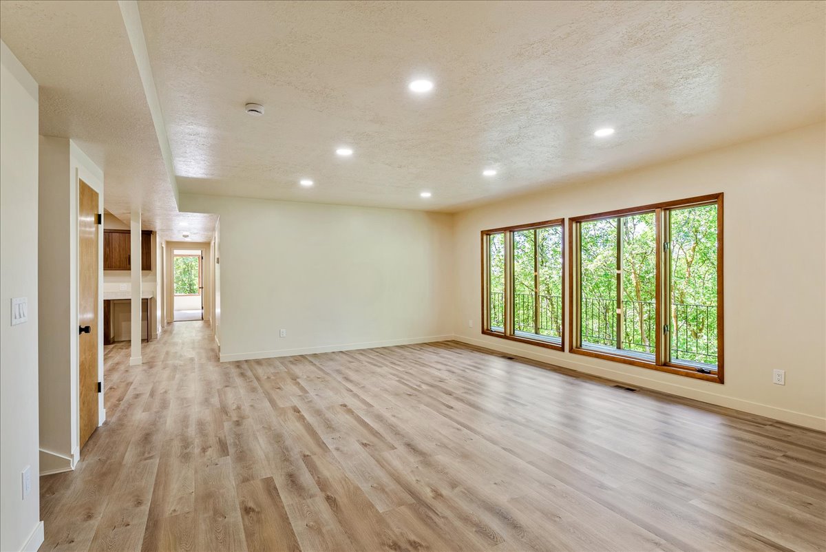 Spacious room featuring wood-finish flooring, recessed lighting, and large windows with wood trim