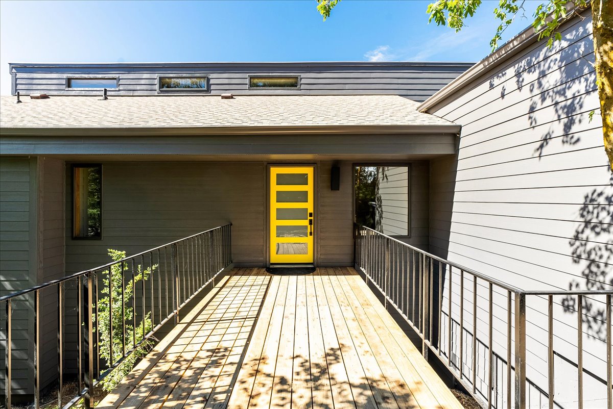 Modern exterior featuring a bright yellow entry door with horizontal glass panels
