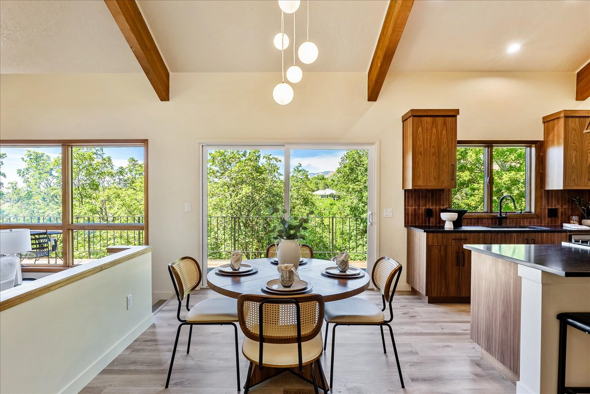 Vaulted ceilings with exposed wood beams, wood-finish flooring, and a modern spherical chandelier