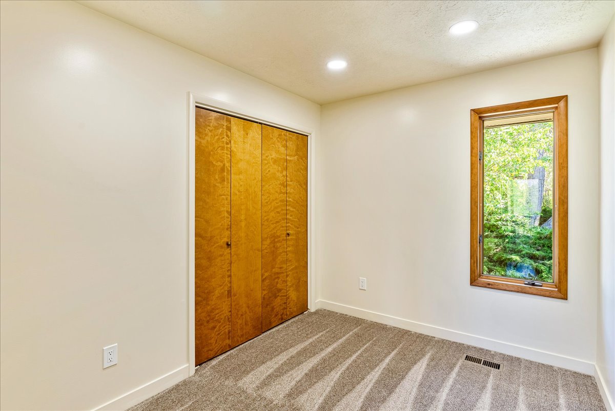 Wood-finish bi-fold closet doors, recessed ceiling lighting, and a single window with wood framing