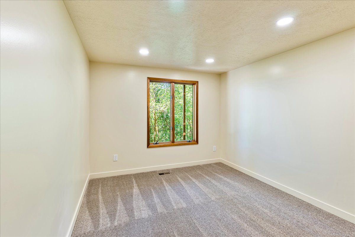 Recessed lighting illuminates this room featuring light-toned walls and gray carpeting