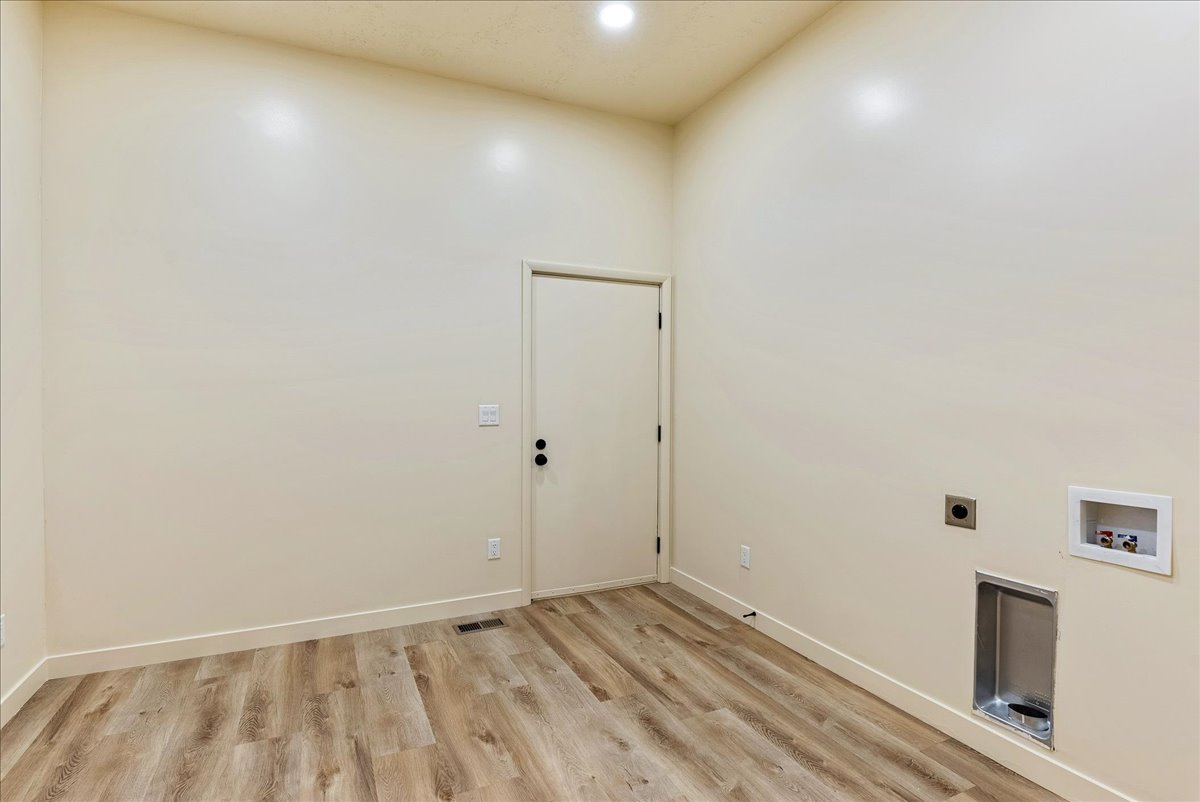 Dedicated laundry area featuring wood-finish flooring and light-toned walls